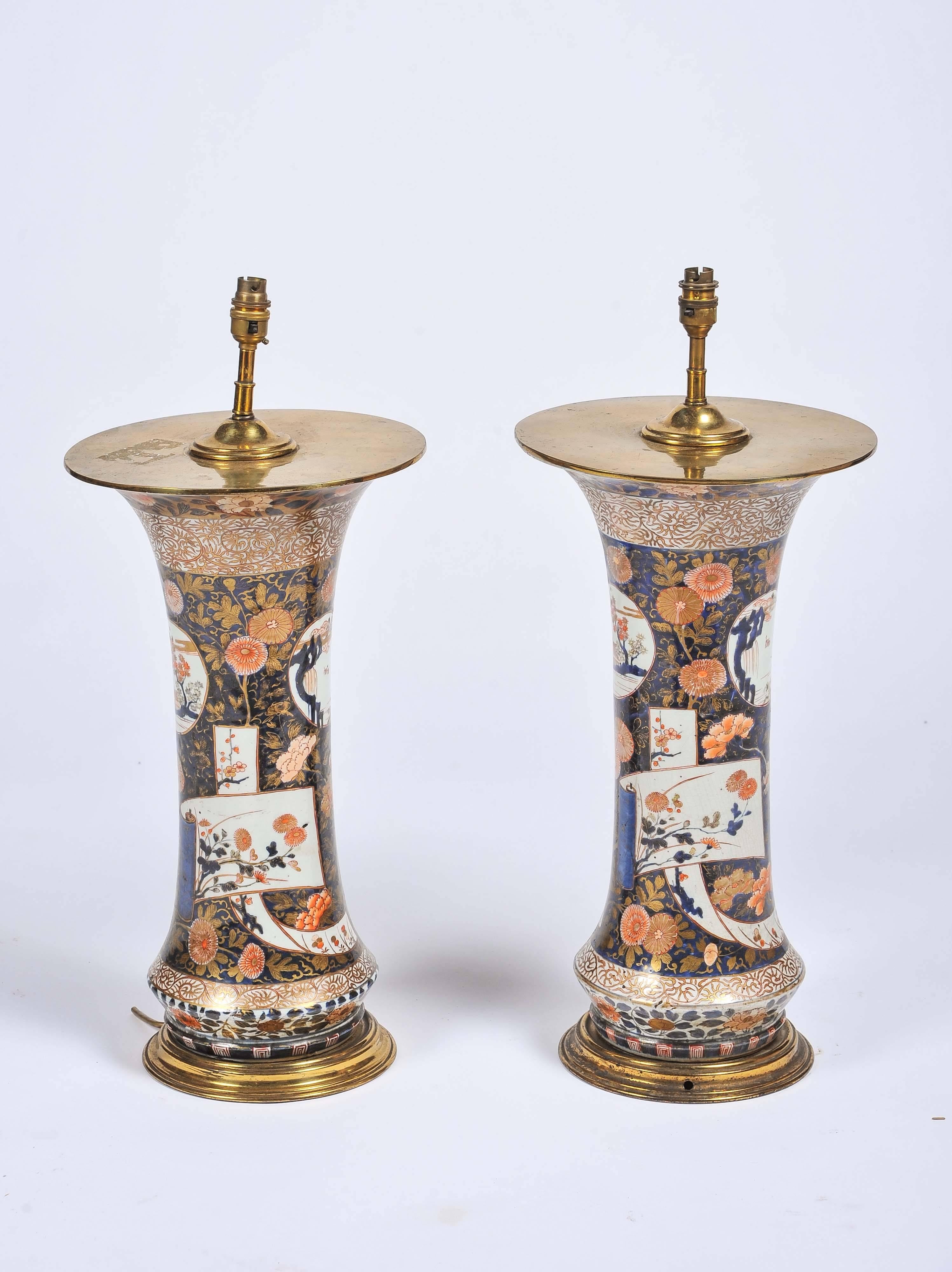 A good quality pair of large 18th century Japanese Arita spill vases, having classical oriental decorated panels set amongst floral and leaf backgrounds. Brass tops and bottoms.