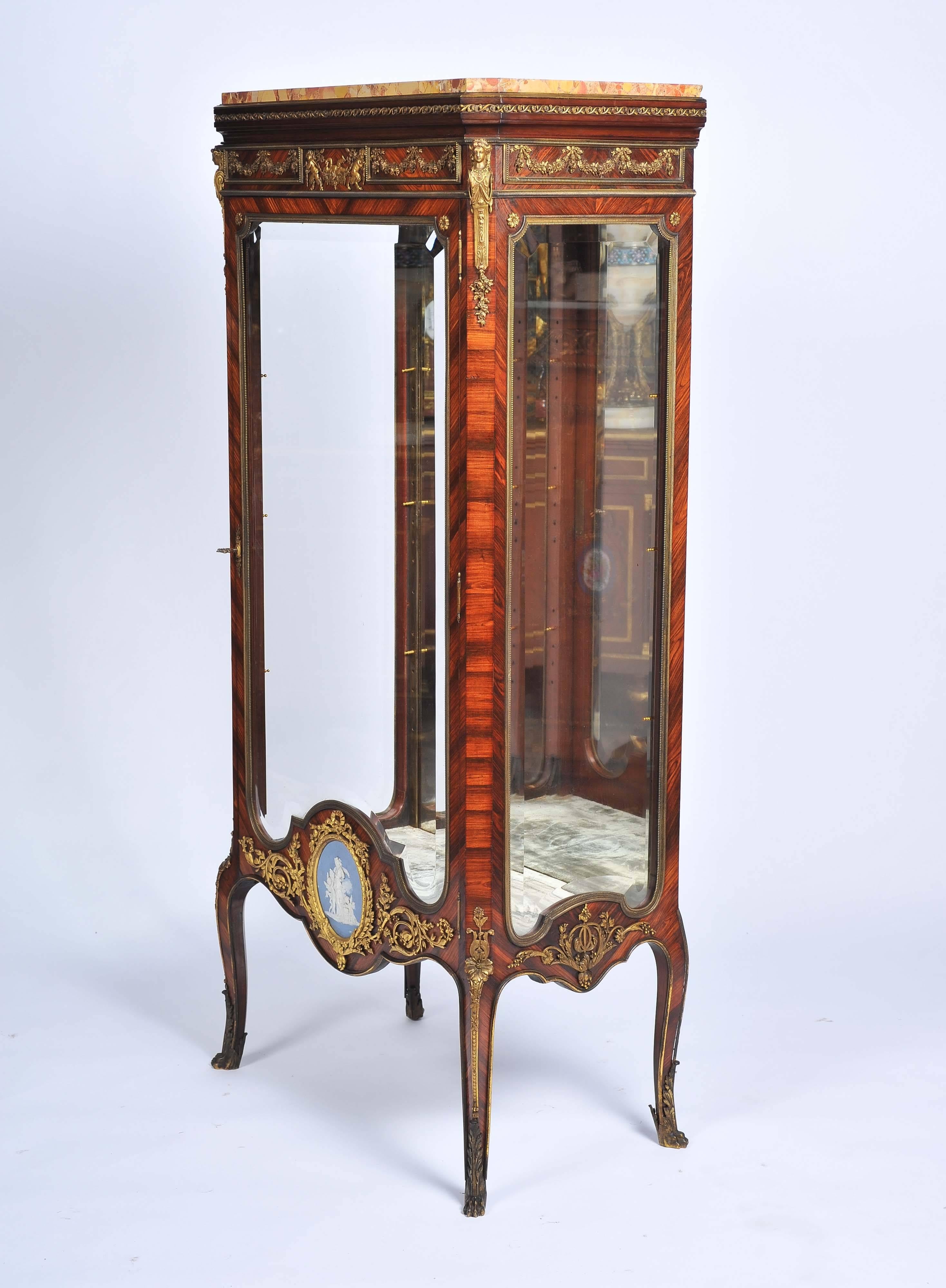 A fine quality 19th century Louis XV style kingwood vitrine, having the original marble top, classical ormolu mounts, bevelled glass, adjustable shelves. A Wedgwood plaque inset to the base of the door and raised on delicate ormolu-mounted cabriole