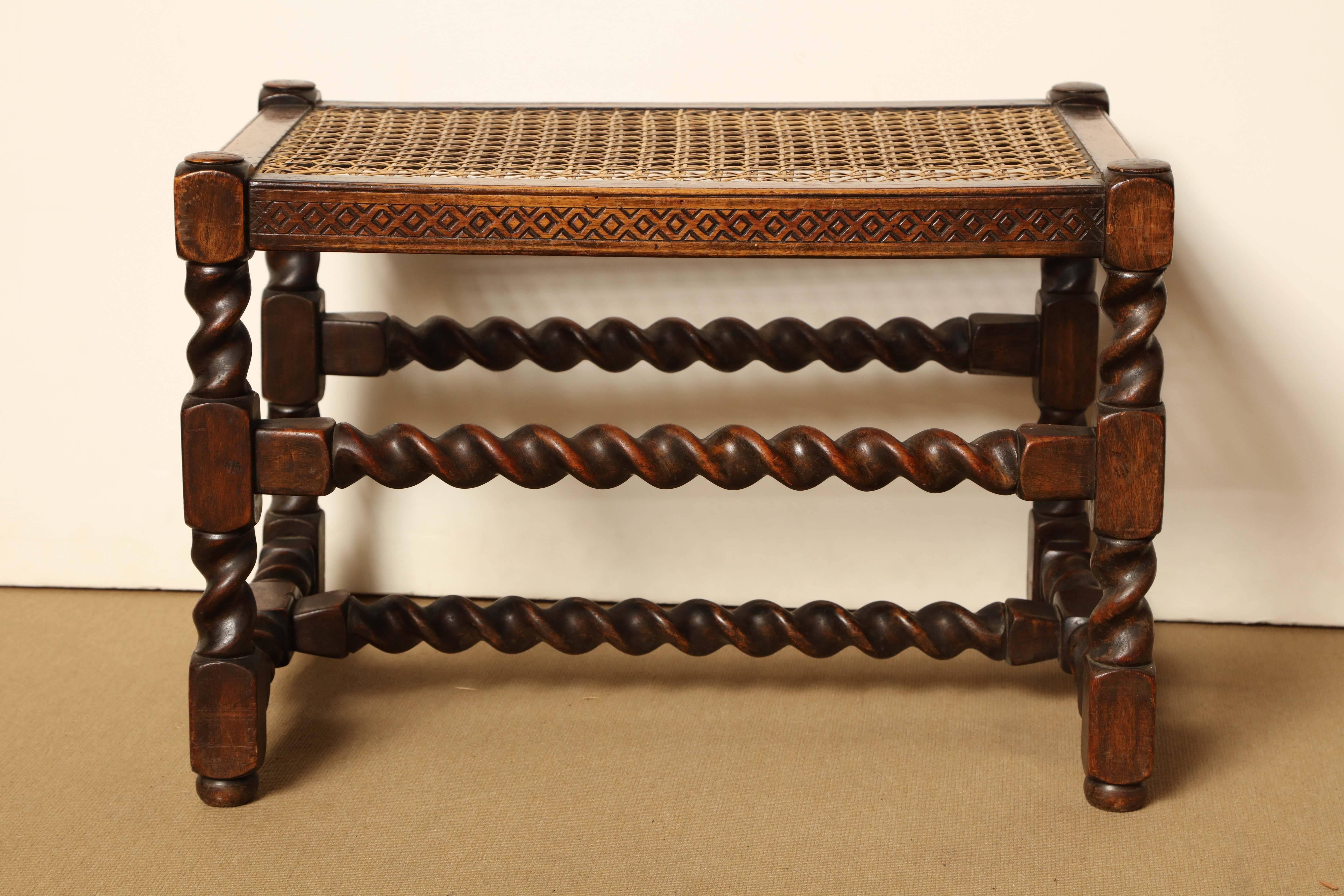 A walnut and caned stool with geometric frieze and barley twist stretchers, 
circa 1920