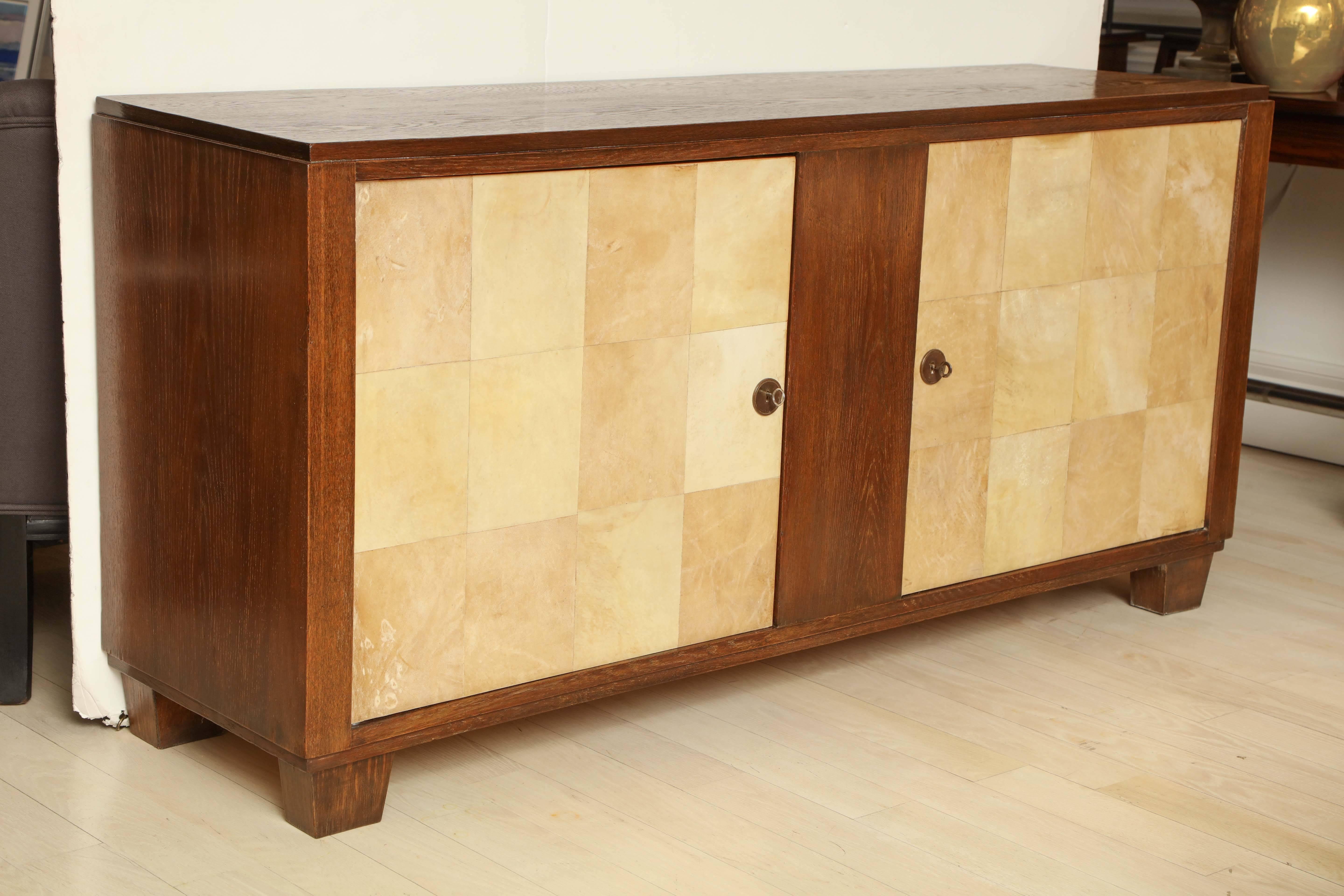 Mid-Century oak credenza with pieced parchment clad doors and two interior shelves, France, circa 1950.