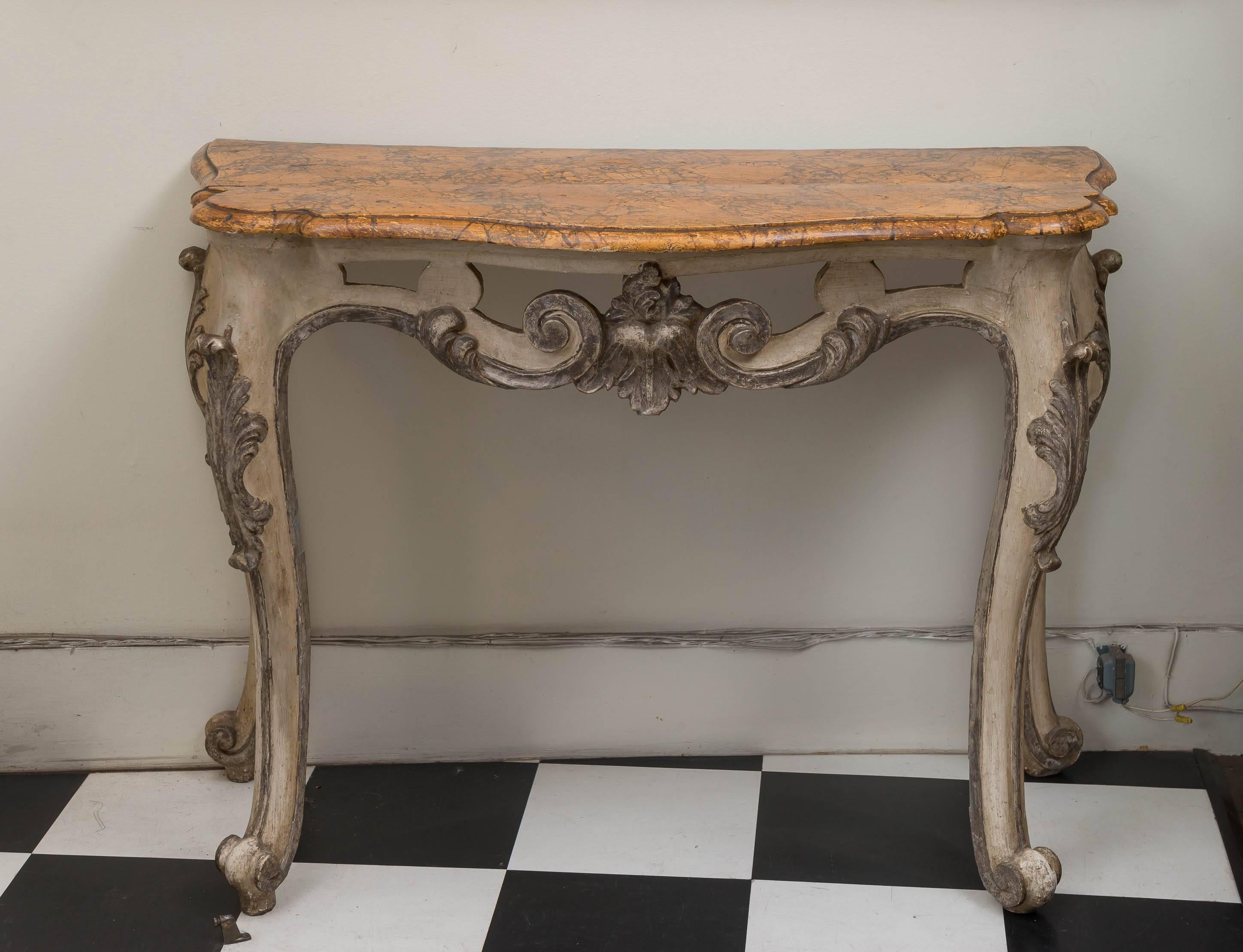 18th century Italian carved wood, paint and silver gilt console table, circa 1775. Good proportions with carved, embellished, bold cabriole legs terminating in a raised volute foot. Faux Sienna marble top of two boards. The two boards separated by a