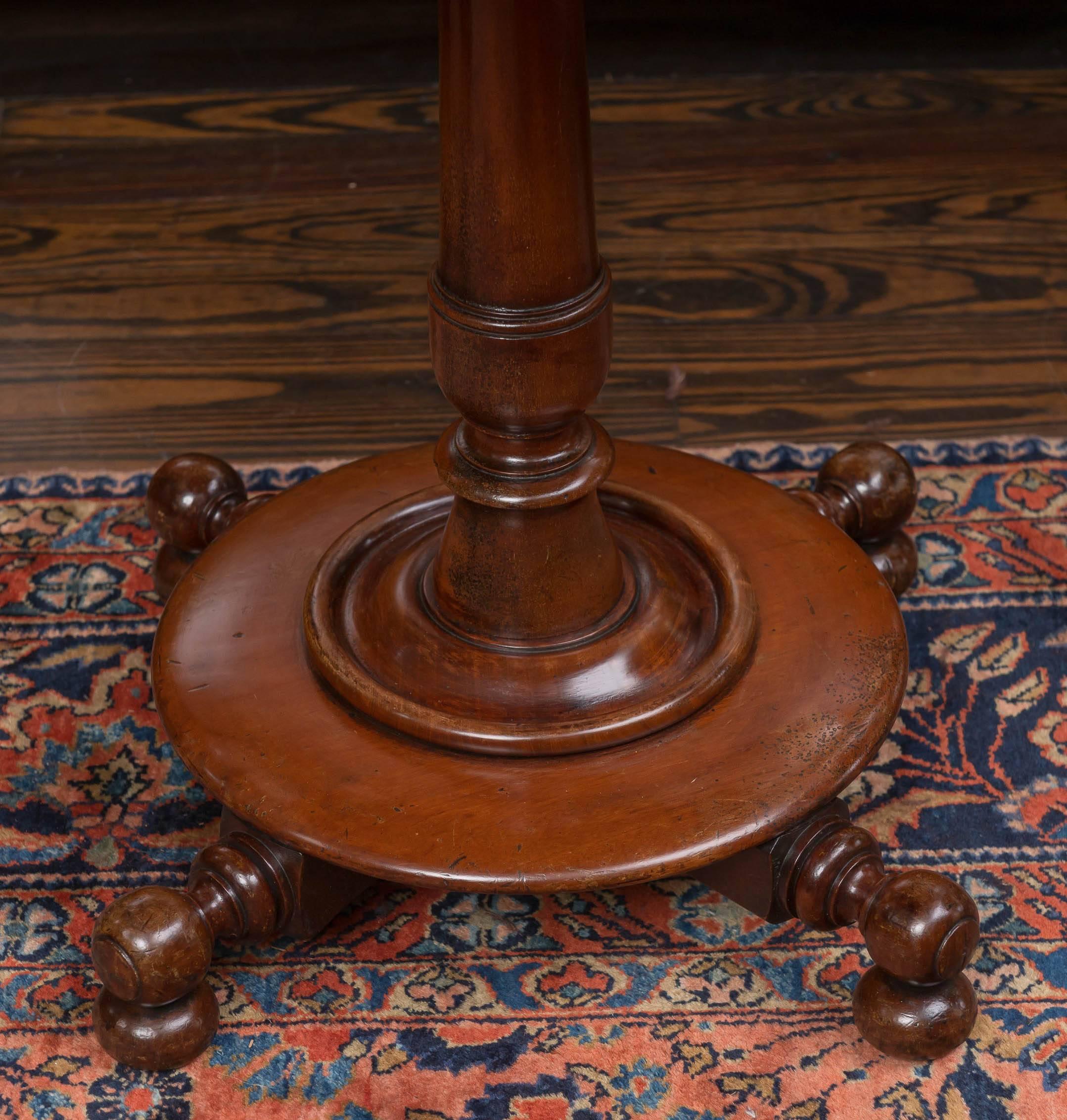 English mahogany George IV tilt-top table, circa 1835.
Good proportions, solid boards and an unusual circular plinth base with turned legs on ball feet. 
Overall mellow color and an old marked finish.