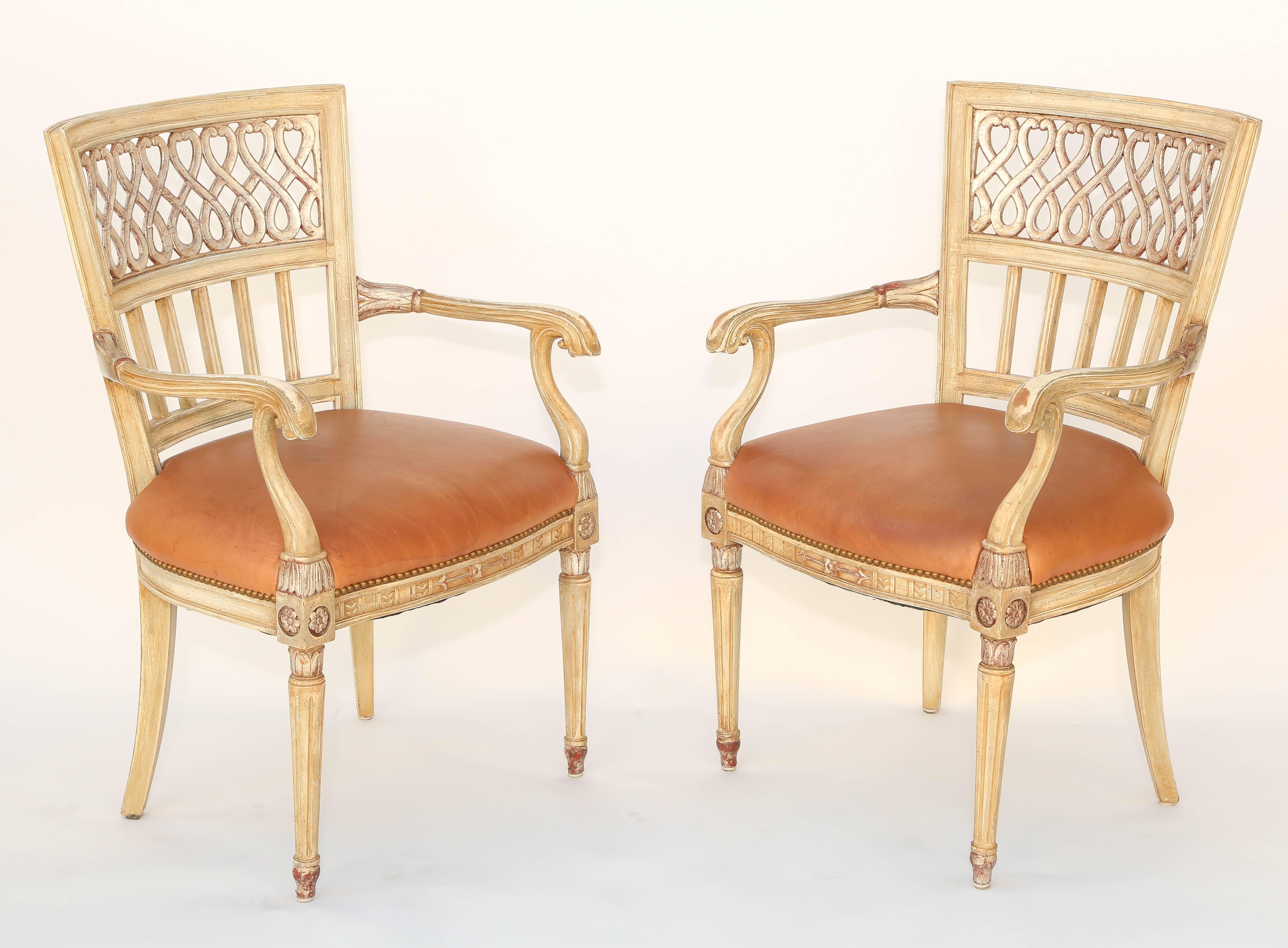 Pair of armchairs, painted and parcel silvergilt finish, having a channeled square, tapering back, inset with scrolling Meander, out swept arm on S-scroll terminals, crown seat in orange leather with nailheads, raised on round, fluted, tapering