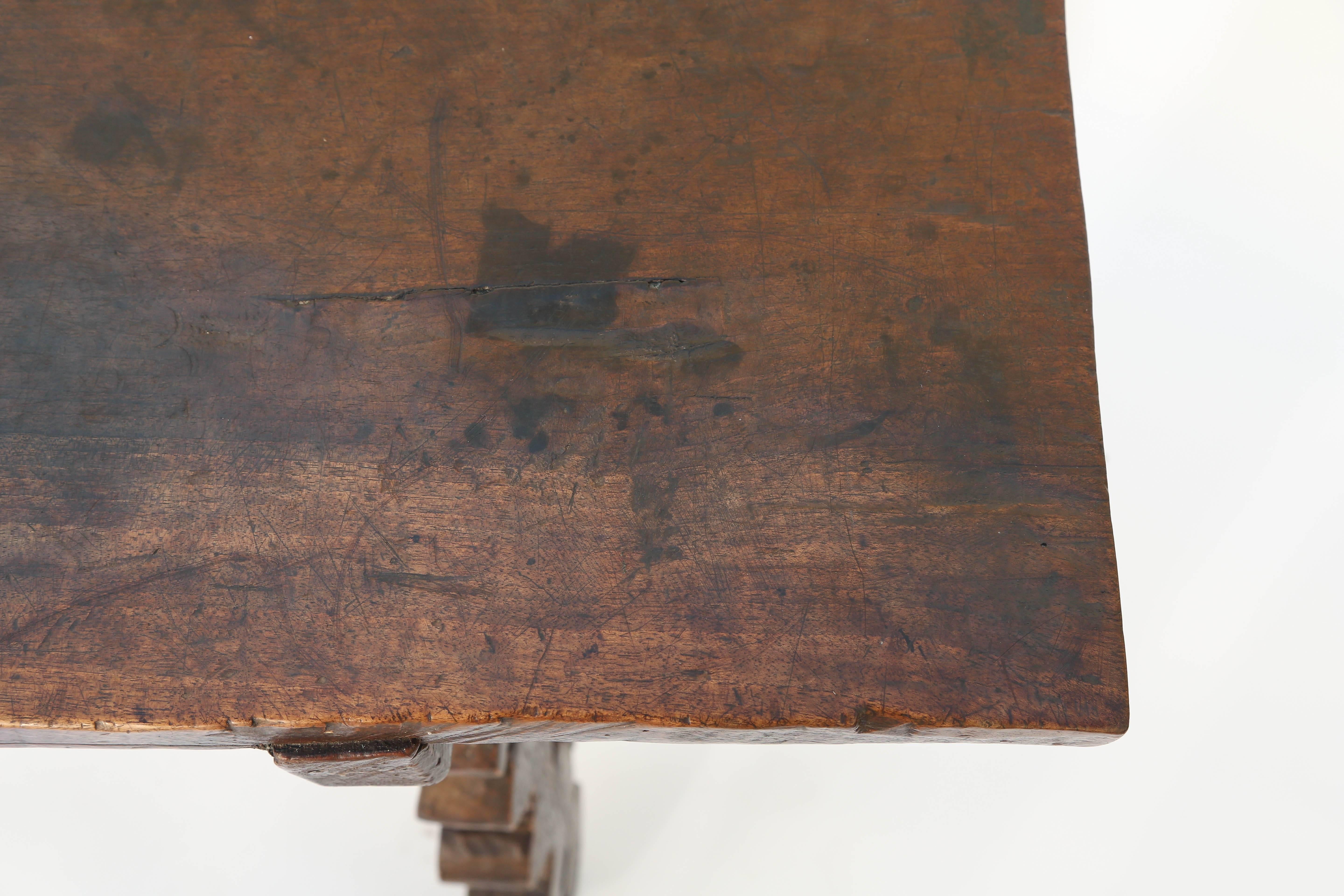 Trestle table of walnut, having a rectangular top of a single plank, raised on lyre-cut legs, and joined by decorative ironwork stretcher.

Stock ID: D3351