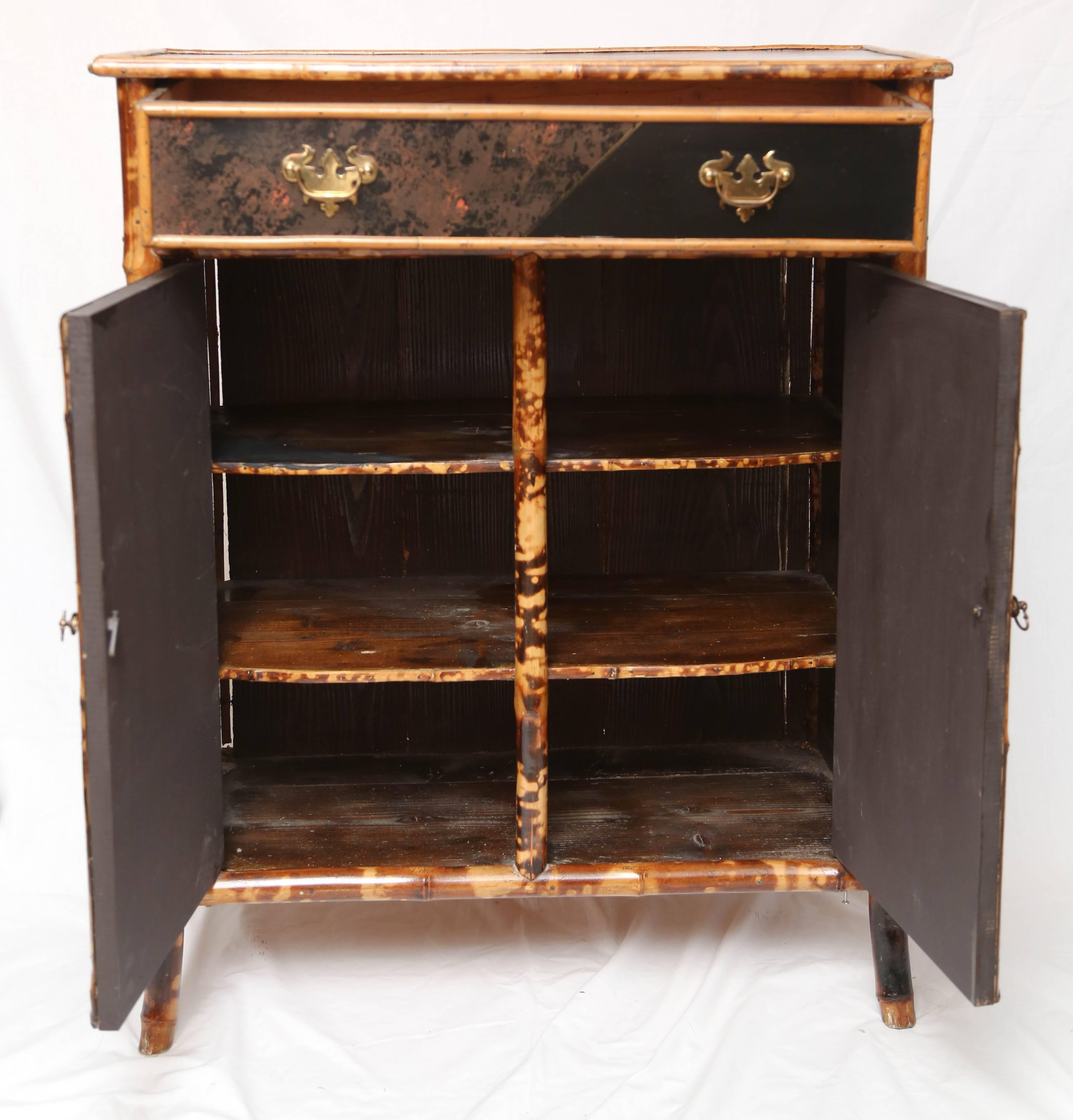 19th century English bamboo with faux front cabinet with a rectangular top with bamboo edge over a long drawer, above a two-door cabinet with two false shelves of books. Measures: Height 37 inches, width 30 inches, depth 15 inches.
 