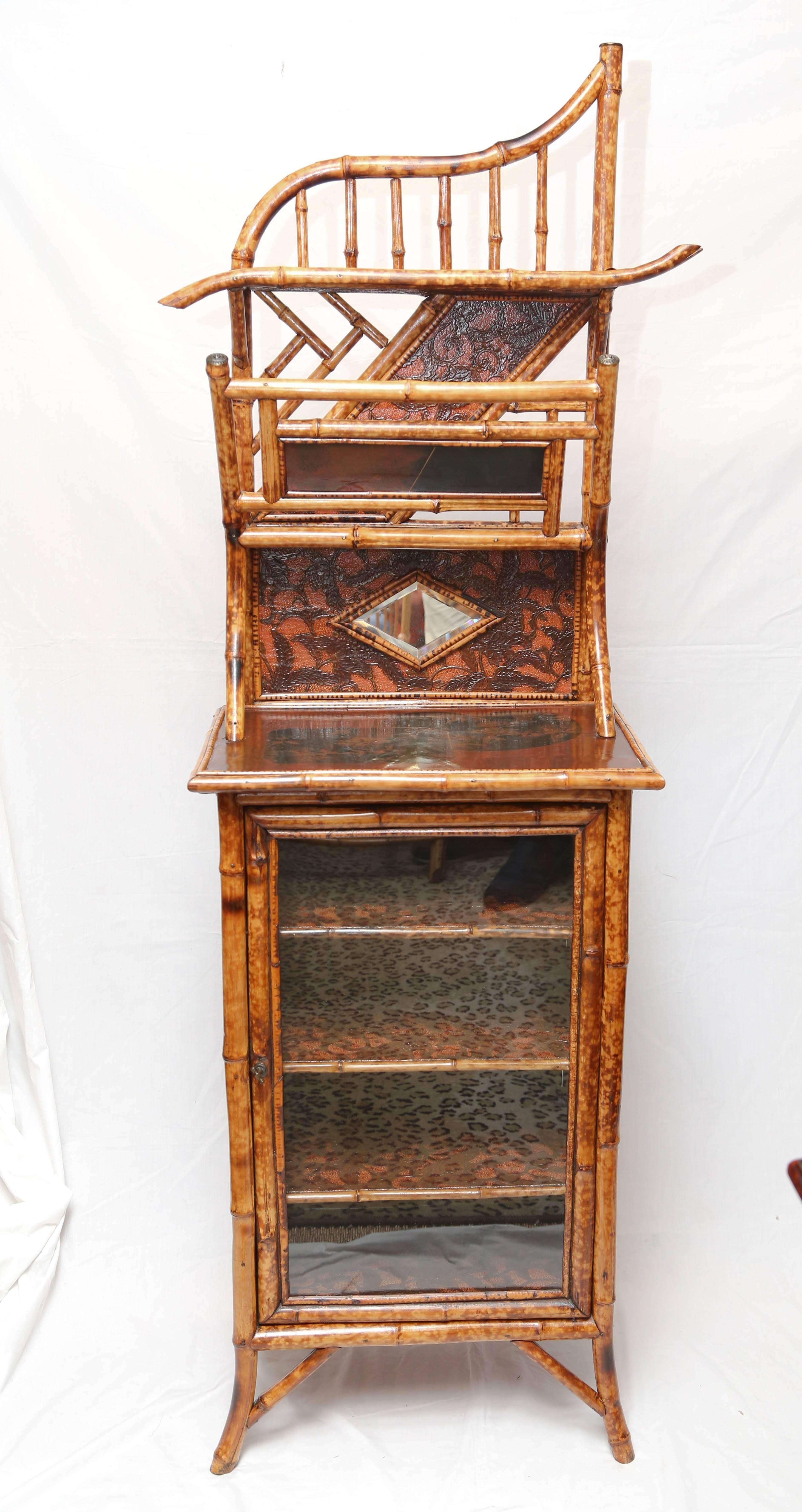 A 19th century English bamboo cabinet with mirror, shelve and leather paper with a Japanning top. Compartment beneath enclosed by glass panel door.
In perfect condition.