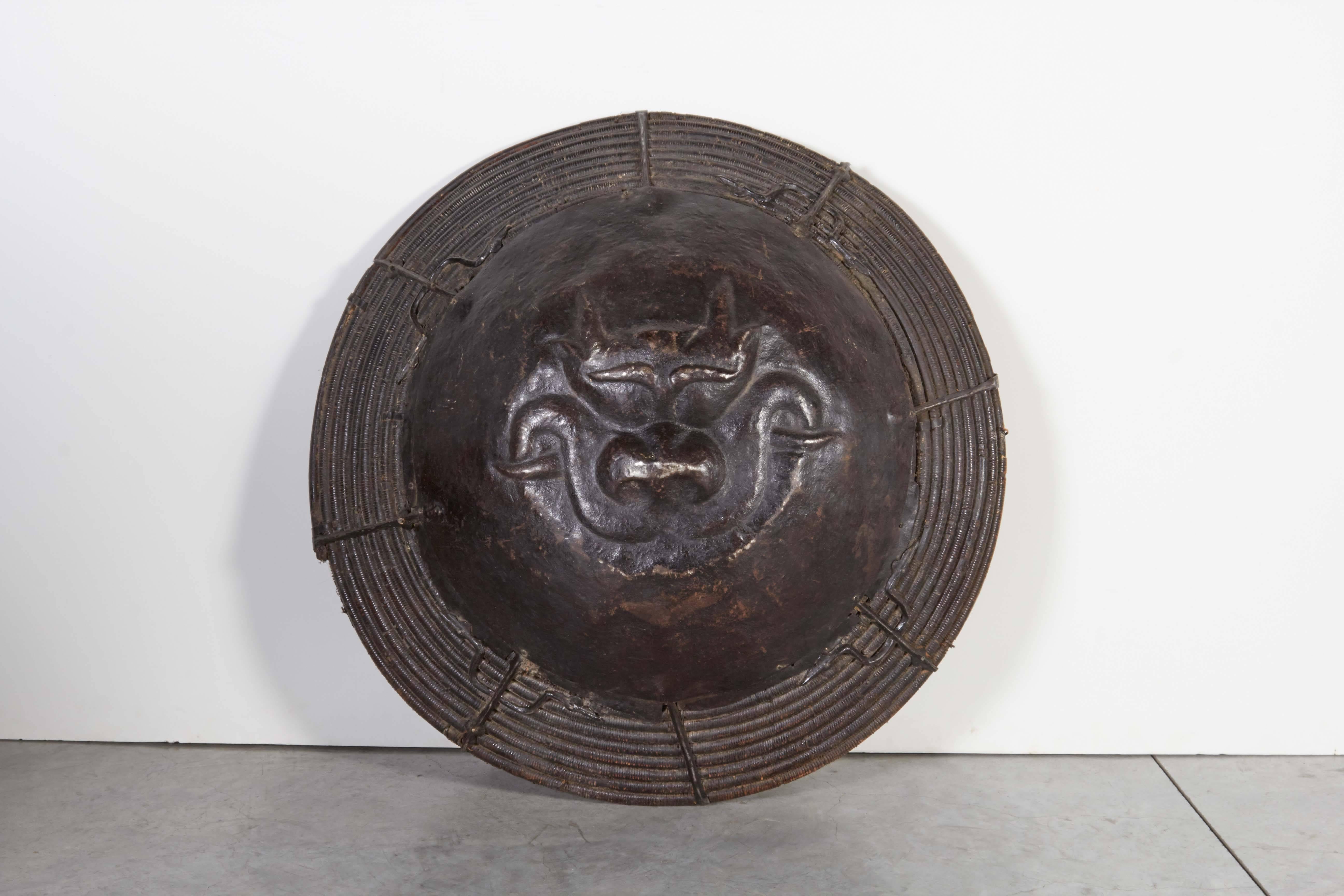 A large and rarely seen woven willow and iron antique Tibetan shield with central image of a very well defined and artfully wrought dragon face. A great piece of craftsmanship and a historical artifact. This piece displays extraordinary detail from