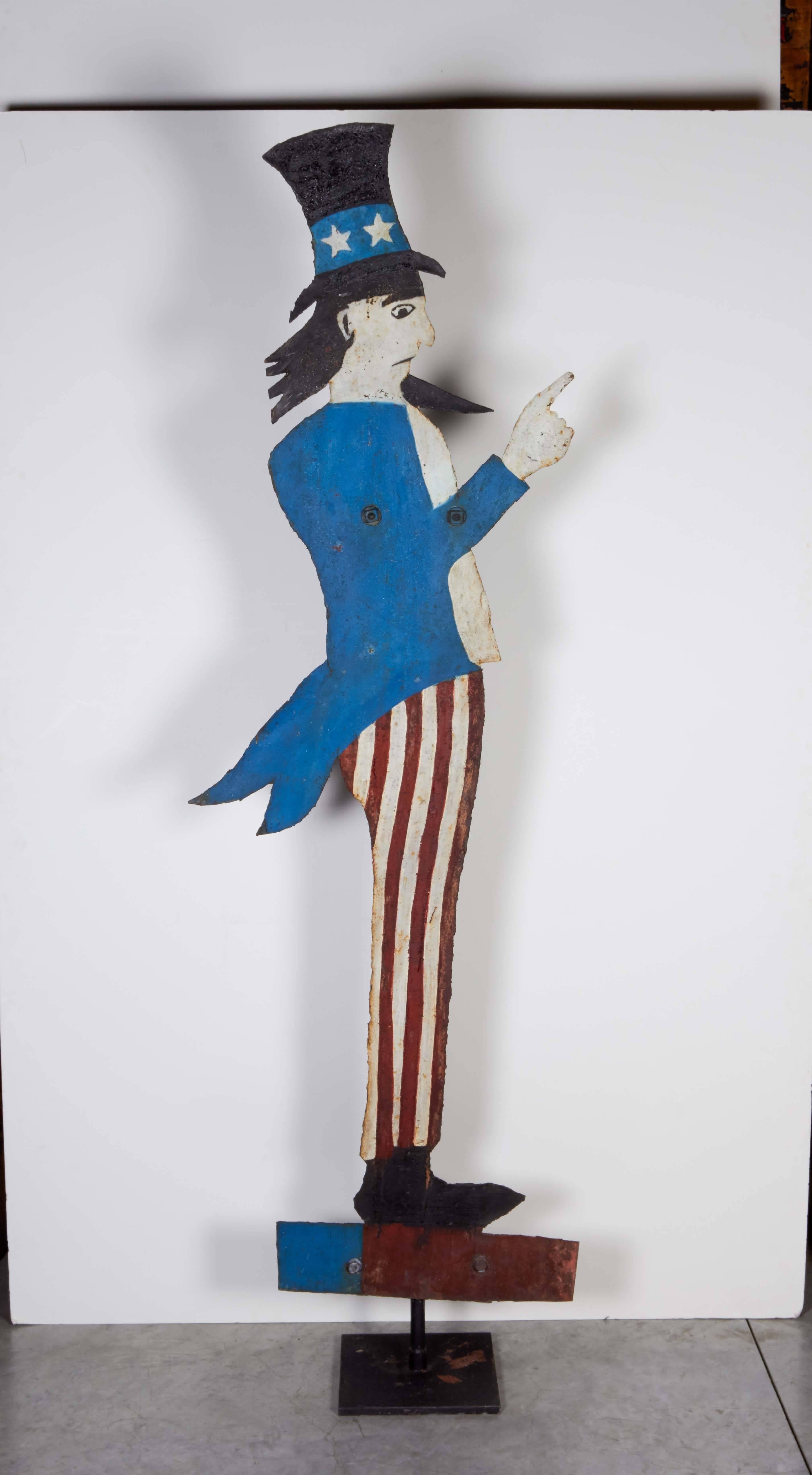 An almost six foot tall die cut steel figure of Uncle Sam with original paint on a stand that allows it to fully revolve. A great image with striking facial features and a strong, expressive hand gesture. A 1960s piece from New England. M937.