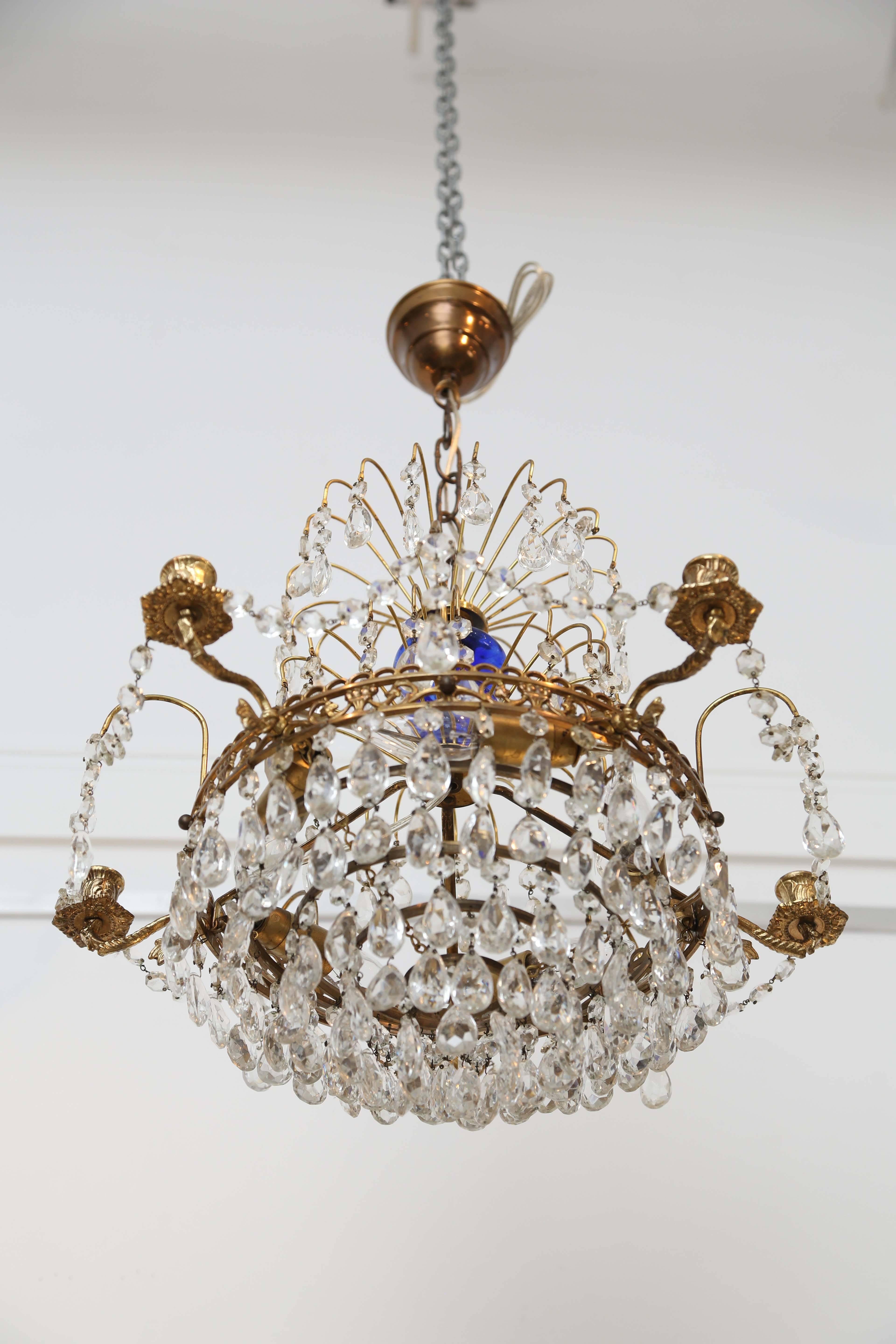 Lovely smaller scale Antique Swedish Louis XVI style brass and crystal chandelier, blue glass centerpiece mounted in the middle of fixture. Five brass candle arms mounted to the carved brass frame.
Five inside candelabra 40 watt max bulbs around