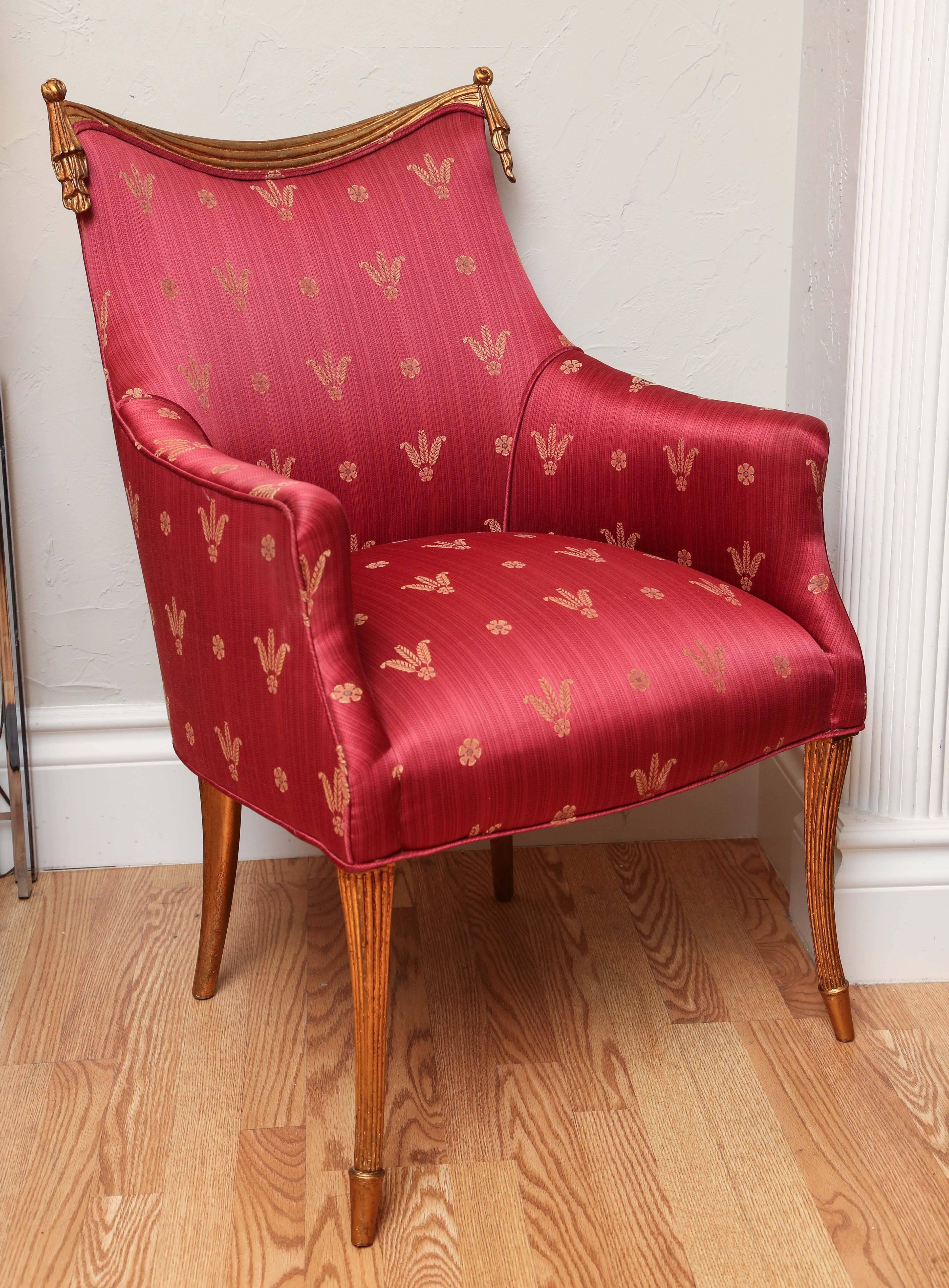 Elegant pair of carved and gilded wood frame Hollywood Regency armchairs. Upholstered in red and gold silk with the Duke of Windsor's three feathers design.