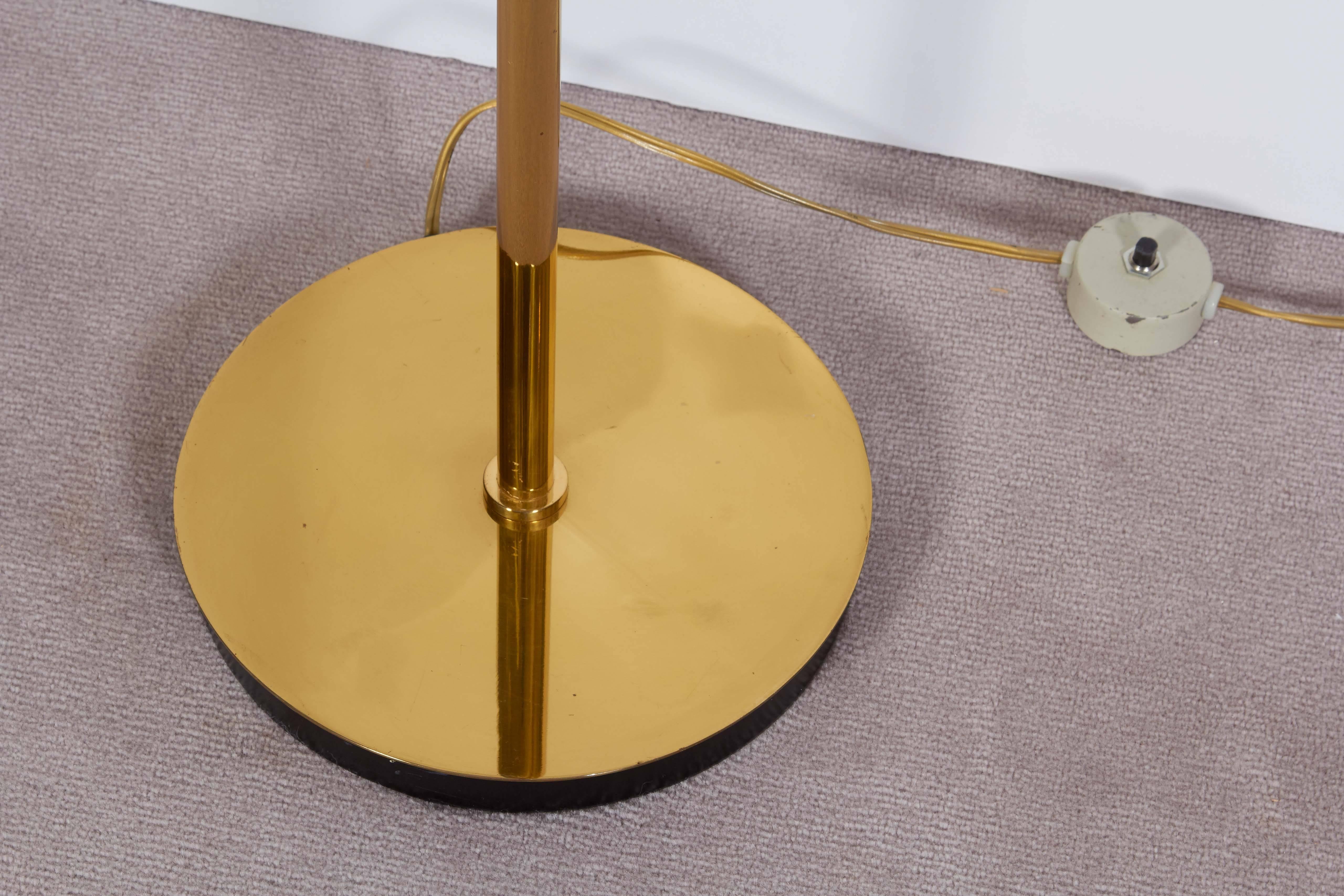  A pair of polished brass reading floor lamps, produced by Nessen Studio, circa 1970s, each with pivoting tent form shade, supported by swing arm on curved adjustable stem. Wiring and socket to US standard. Very good vintage condition, with some