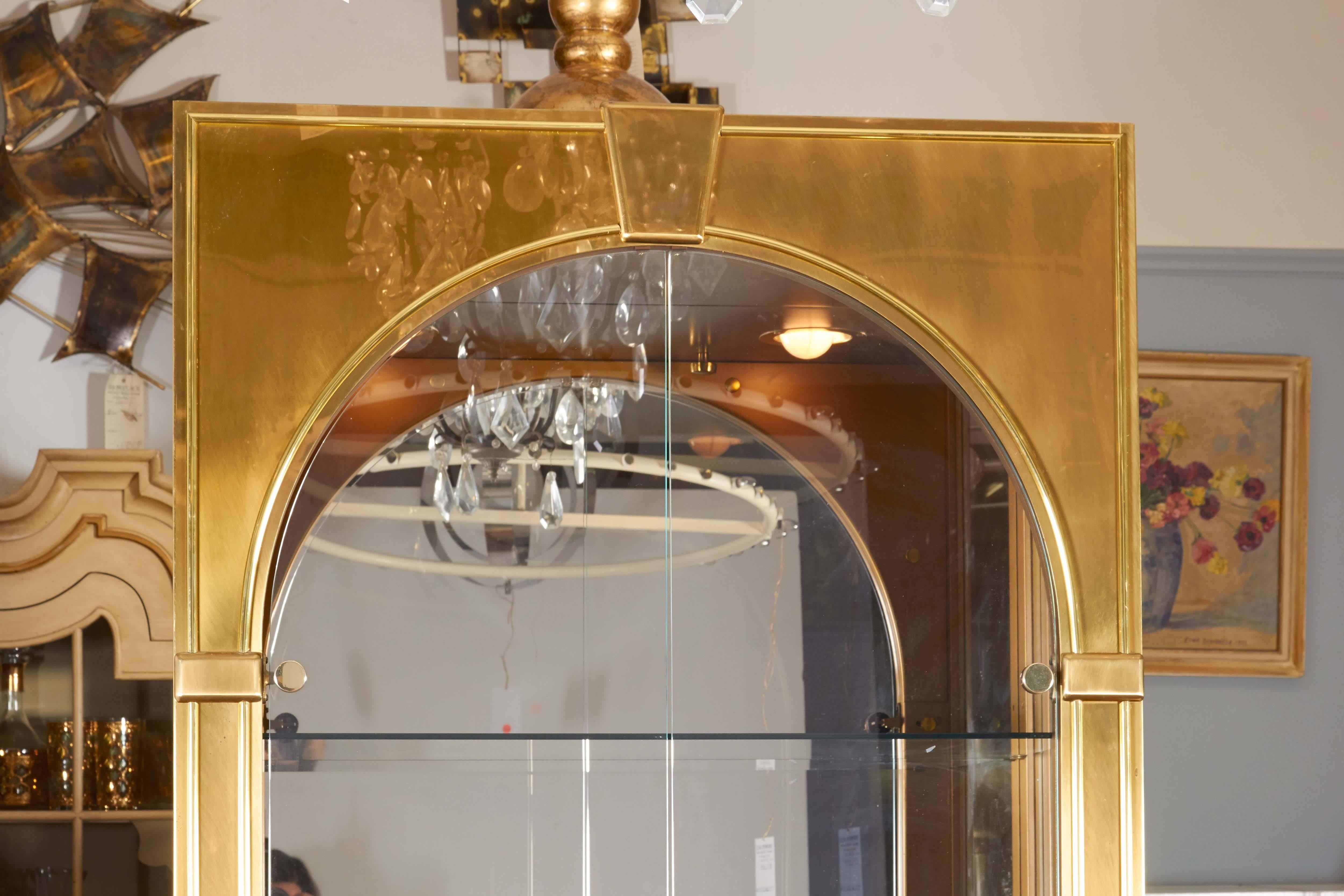 A pair of impressive vitrines in the classical Palladian style, manufactured by Mastercraft, circa 1970s, each with glass windows against brass frames, including two-door arched front, the interior with three glass shelves, above lower two-door