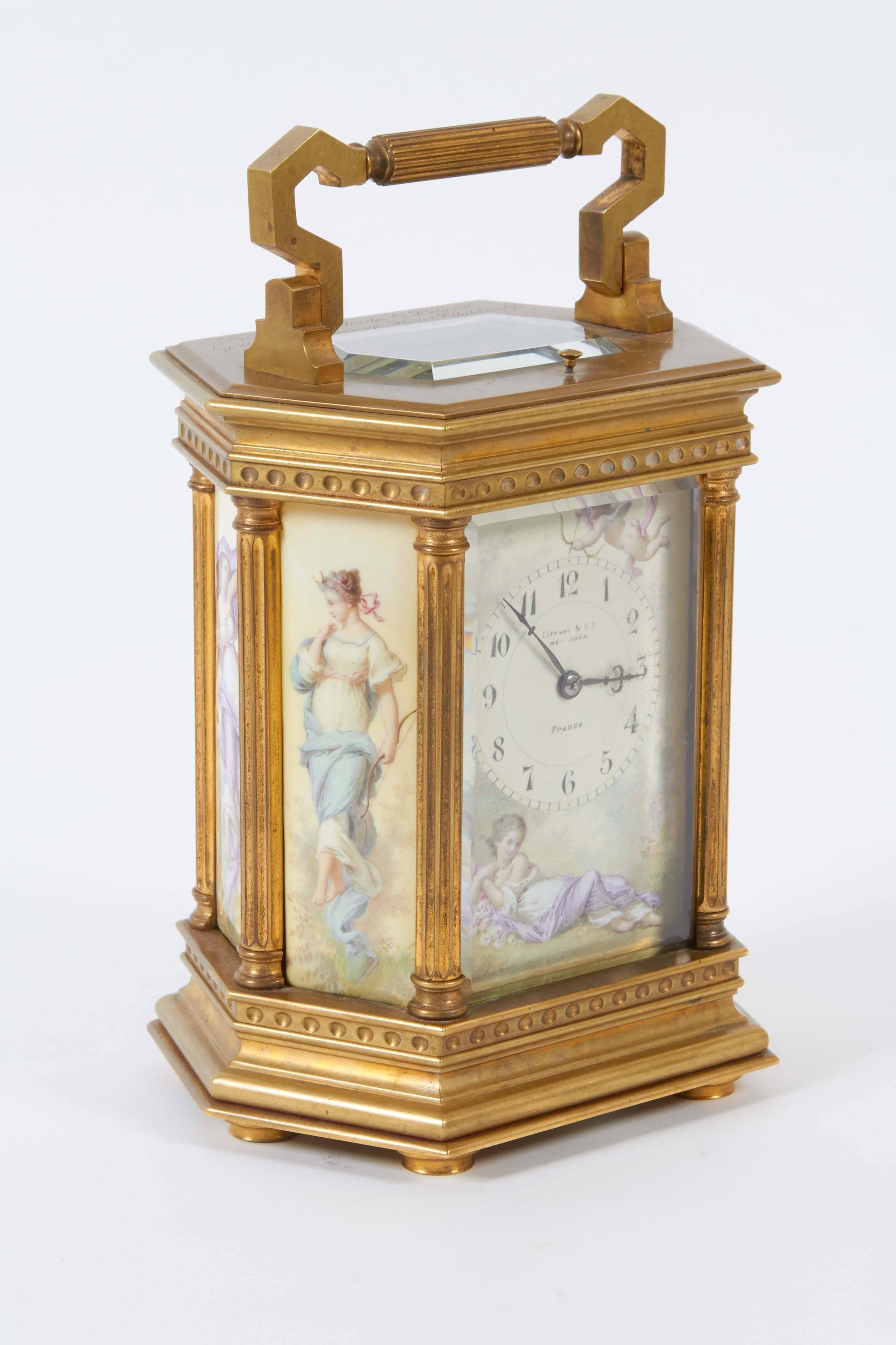 A French early 20th century carriage clock by Tiffany & Co., of hexagonal form in gilt bronze, with neoclassical architectural elements, framed by fluted columns and decorative panels, depicting classical maidens on four sides, one figure