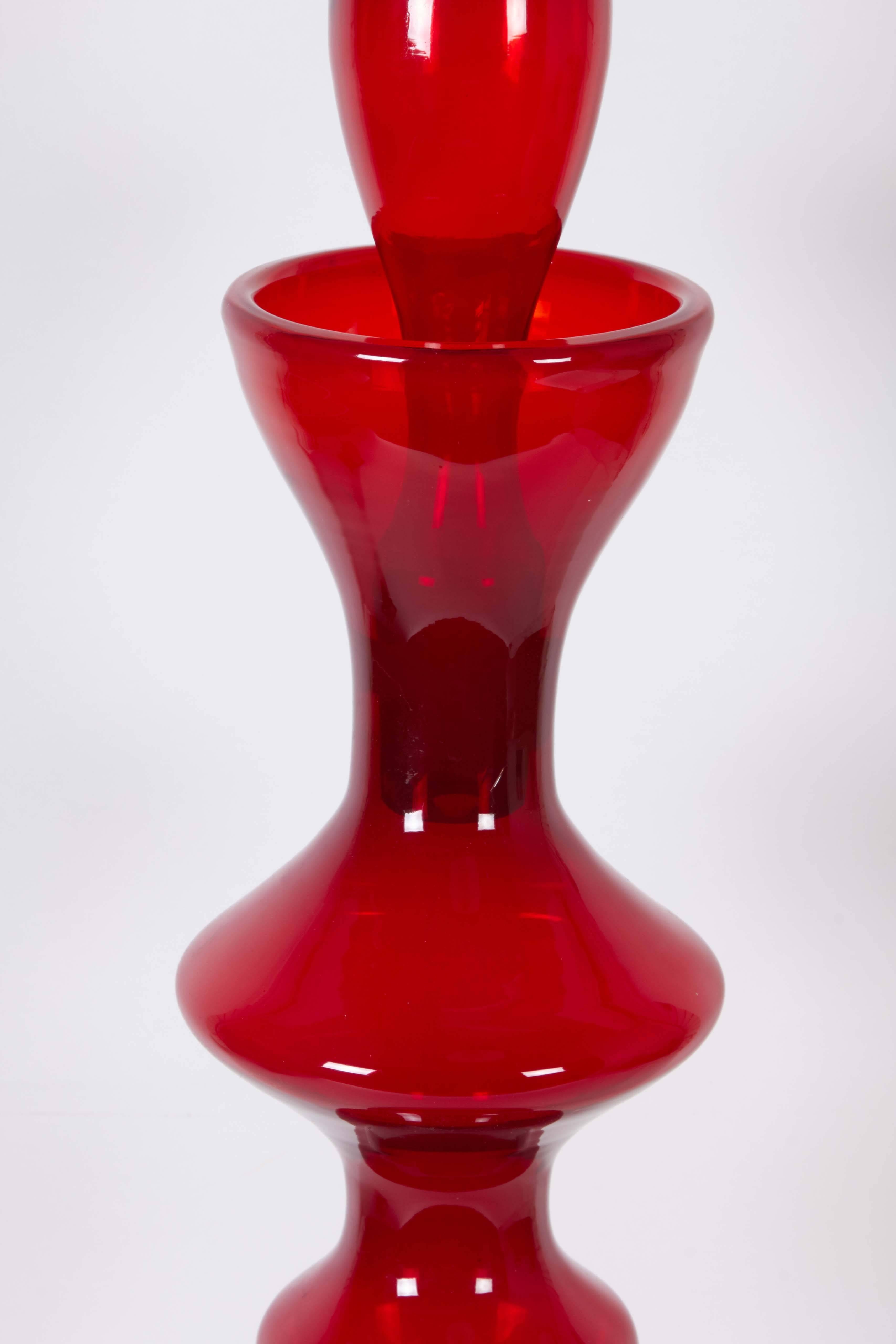 A huge decanter designed by Wayne Husted in 1959 for Blenko of Milton, West Virginia, produced circa 1960-1961, comprised of ruby red blown glass, formed into a 'chess piece' shape. Markings include [Blenko] acid etched to the underside of the
