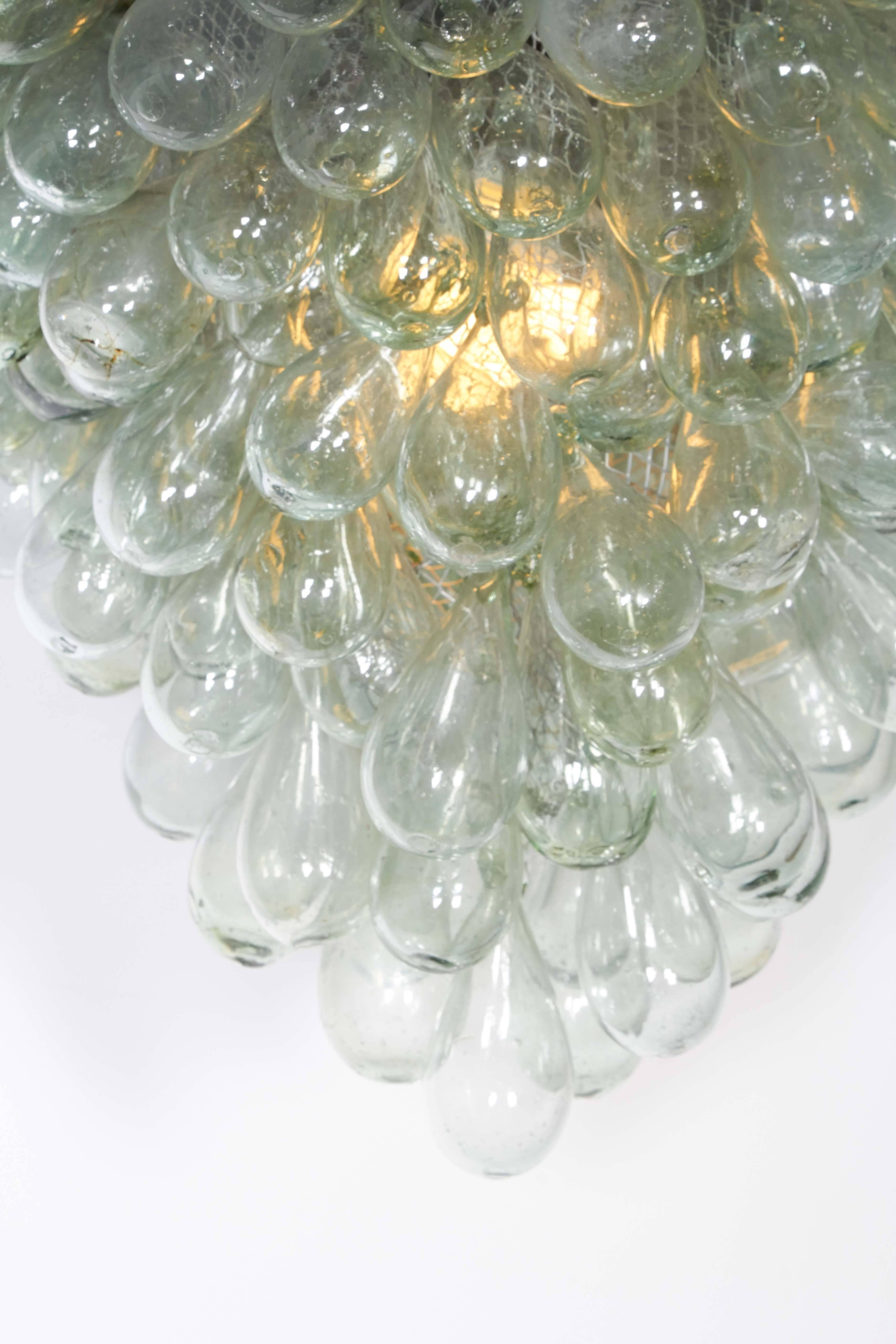 A modern light fixture, featuring blown glass styled as a grape cluster, suspended from circular flush mount canopy. Wiring and socket to US standard, requires single bulb. Very good condition, wear consistent with age and use.

10922