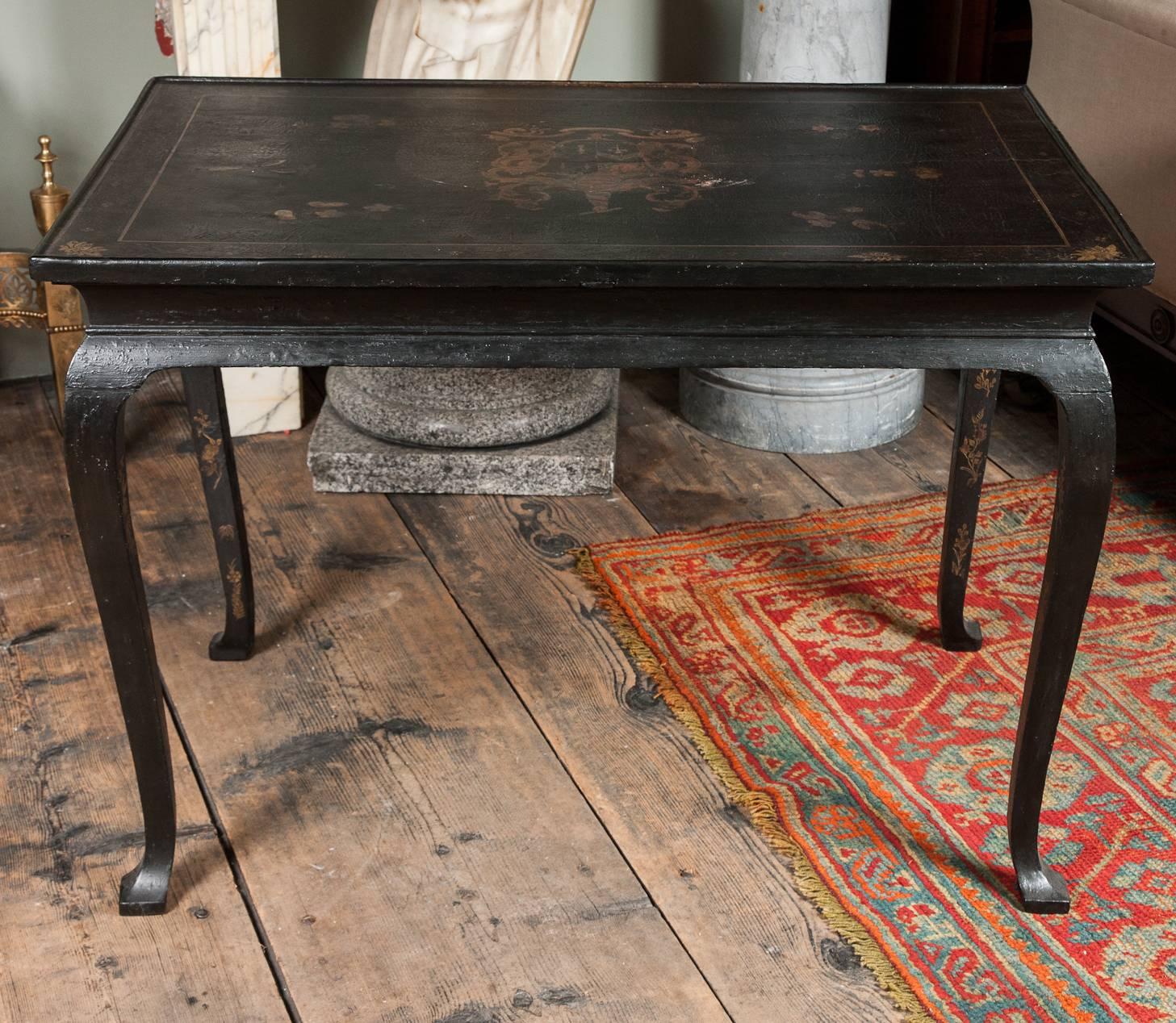 A George I black Japanned centre table. The moulded rectangular top with central coat of arms and foliate border, painted frieze, on squared cabriole legs with pointed pad feet.