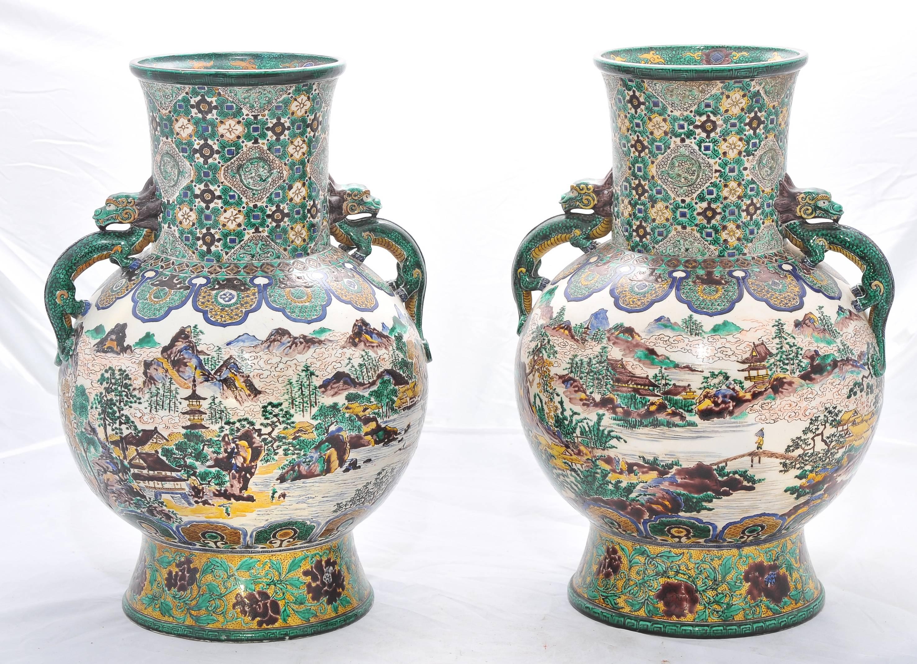 A large and decorative pair of 19th century Japanese Kutani vases. Having an unusual Green background with classical symbols and motifs. Mythical creators as handles. The central scene depicting lakes, mountains and pagoda topped buildings.