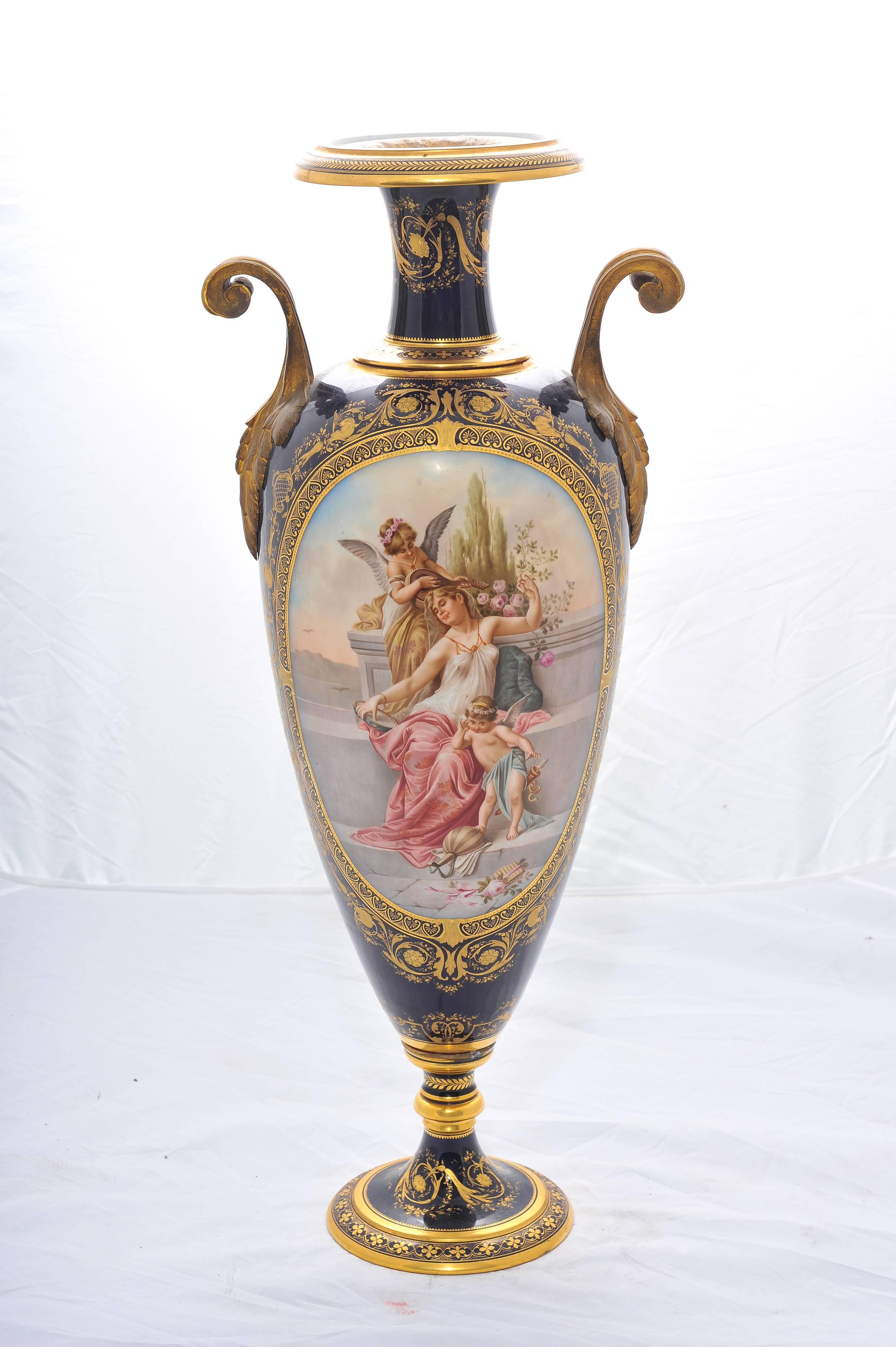 A beautiful French 'Sèvres' porcelain two handle vase, depicting a classical scene of a young maiden playing music with cherubs around her. Set in a dark blue back ground and gilded decoration.