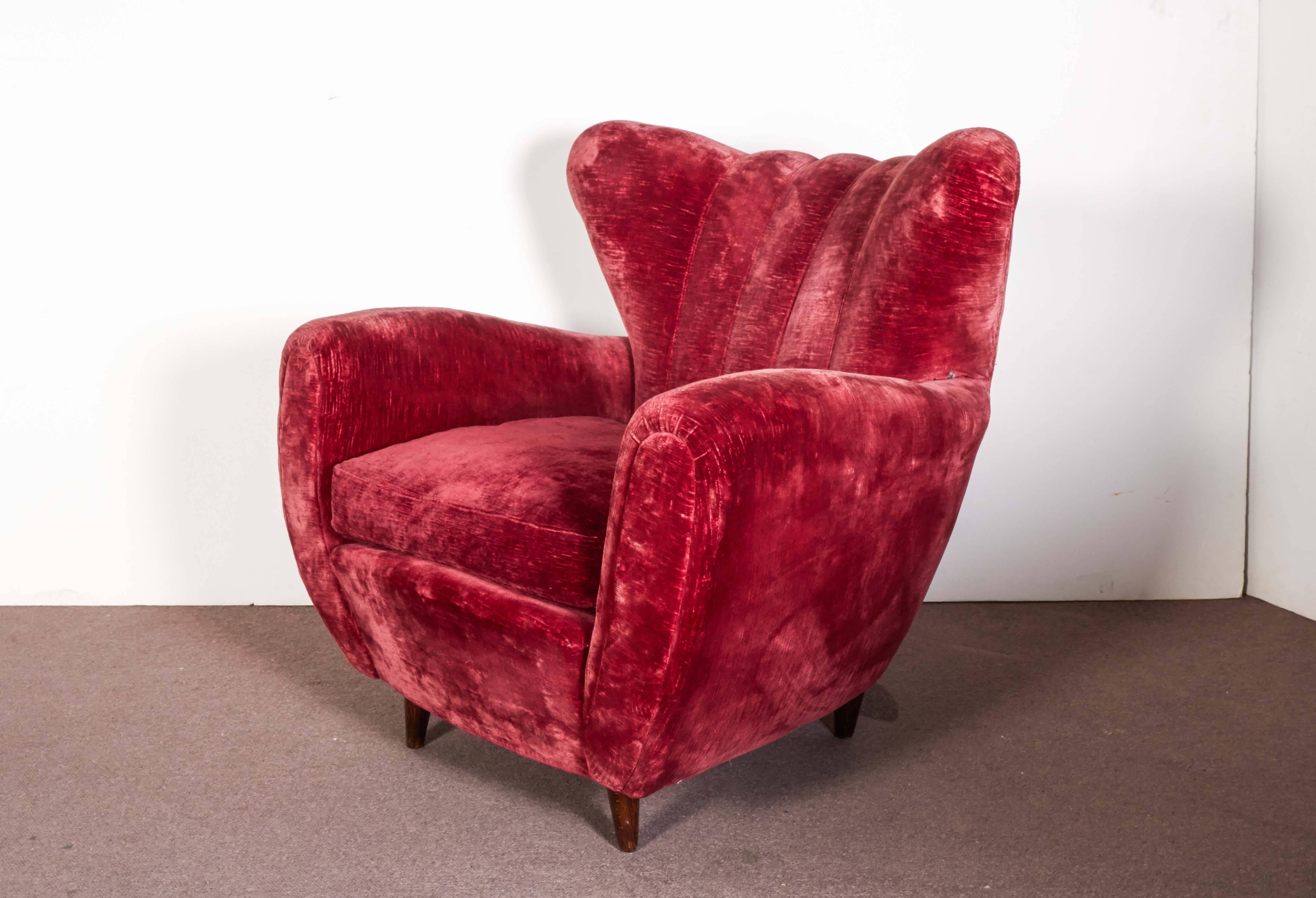Pair of oversized and extremely comfortable chairs with winged backs in original magenta colored crushed velvet, attributed to Guglielmo Ulrich. The chairs feature a slightly barrel shaped anthropomorphic body with fluted backrest, flanked by
