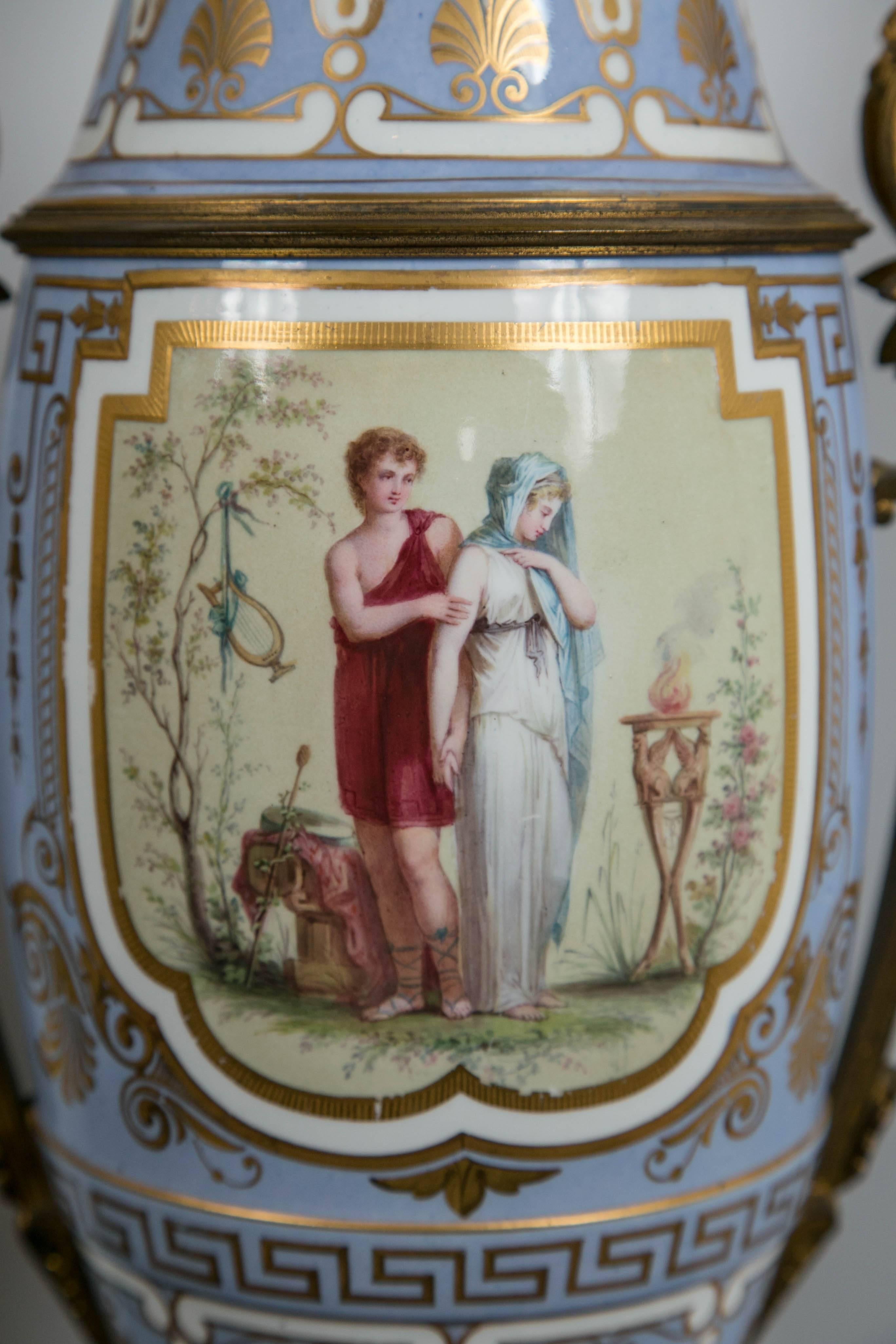 A beautiful pair of table lamps, made during the time that such were kerosene or oil burning. There is the original burner on top of the porcelain.
Pale blue ground surrounds hand-painted plaques of romantic couples, in the neoclassical manner. The