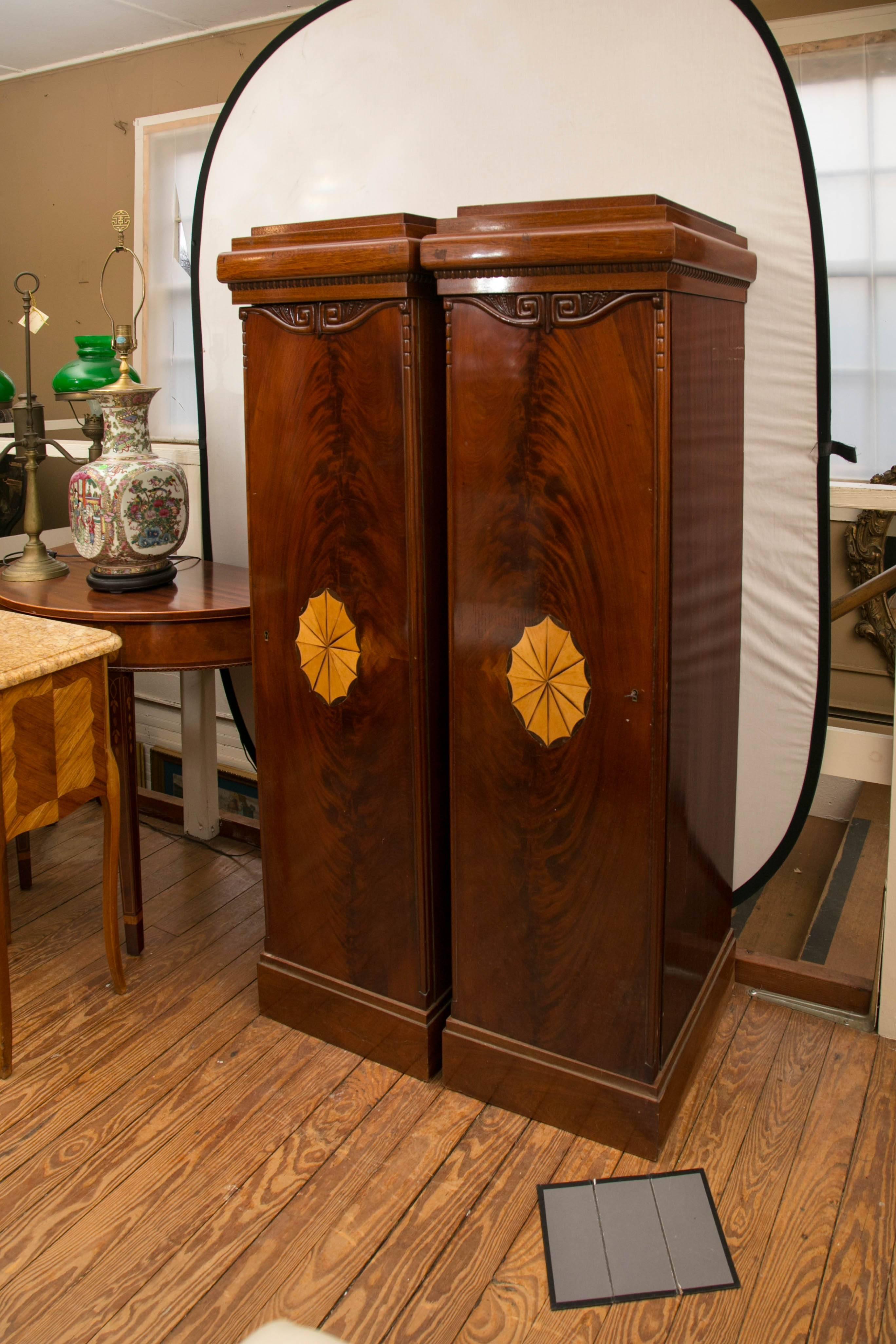 Each mahogany pedestal with a cabinet door, decorated with an inlay oval oof satinwood, hand carving and a veneer of flame mahogany. Inside are four removable shelves, each measuring 15 .75 deep amd 12 wide. 
The tops are stepped and there is a