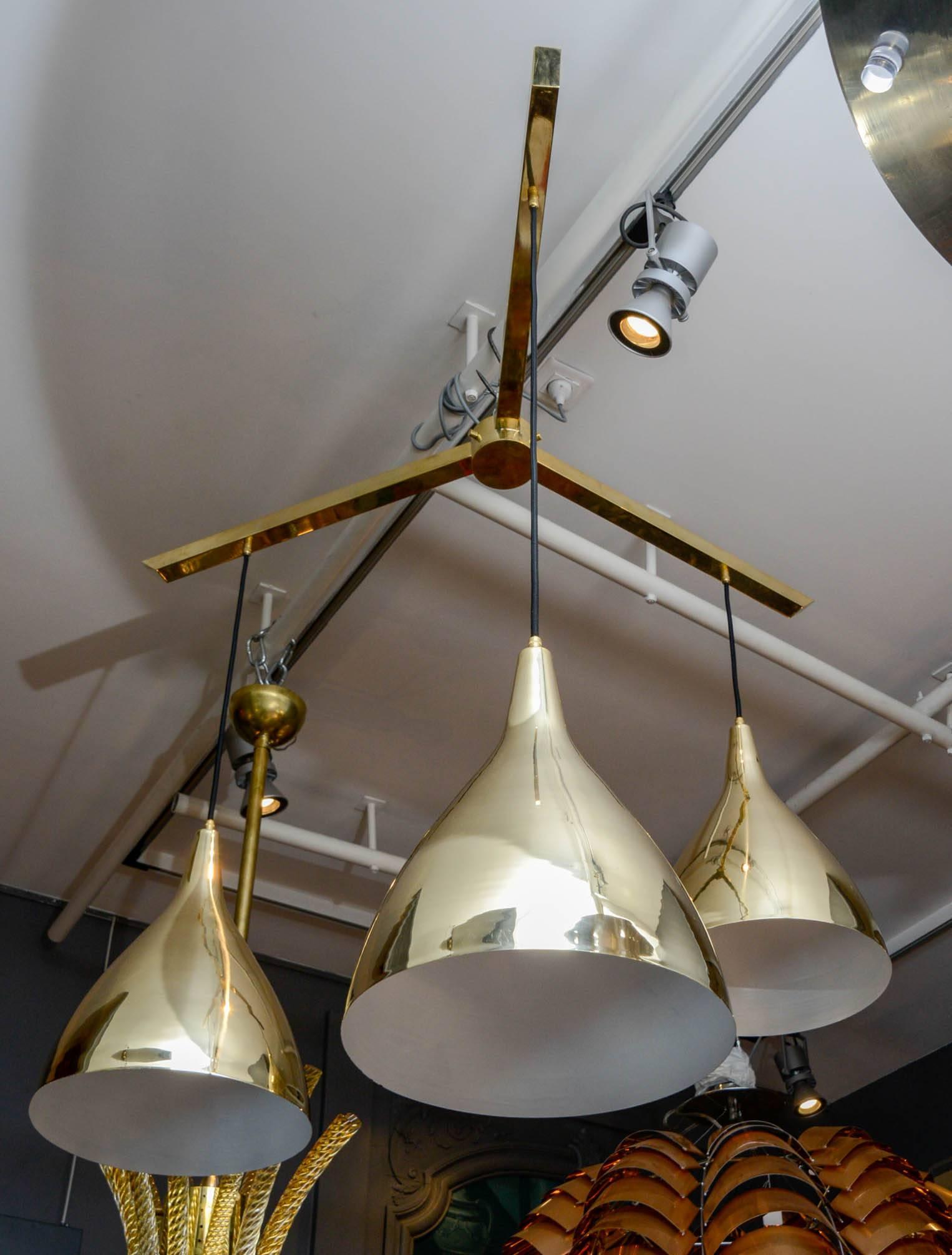 Pair of large suspensions made of three big brass shades hanged by fabric wires from a three arms structure.