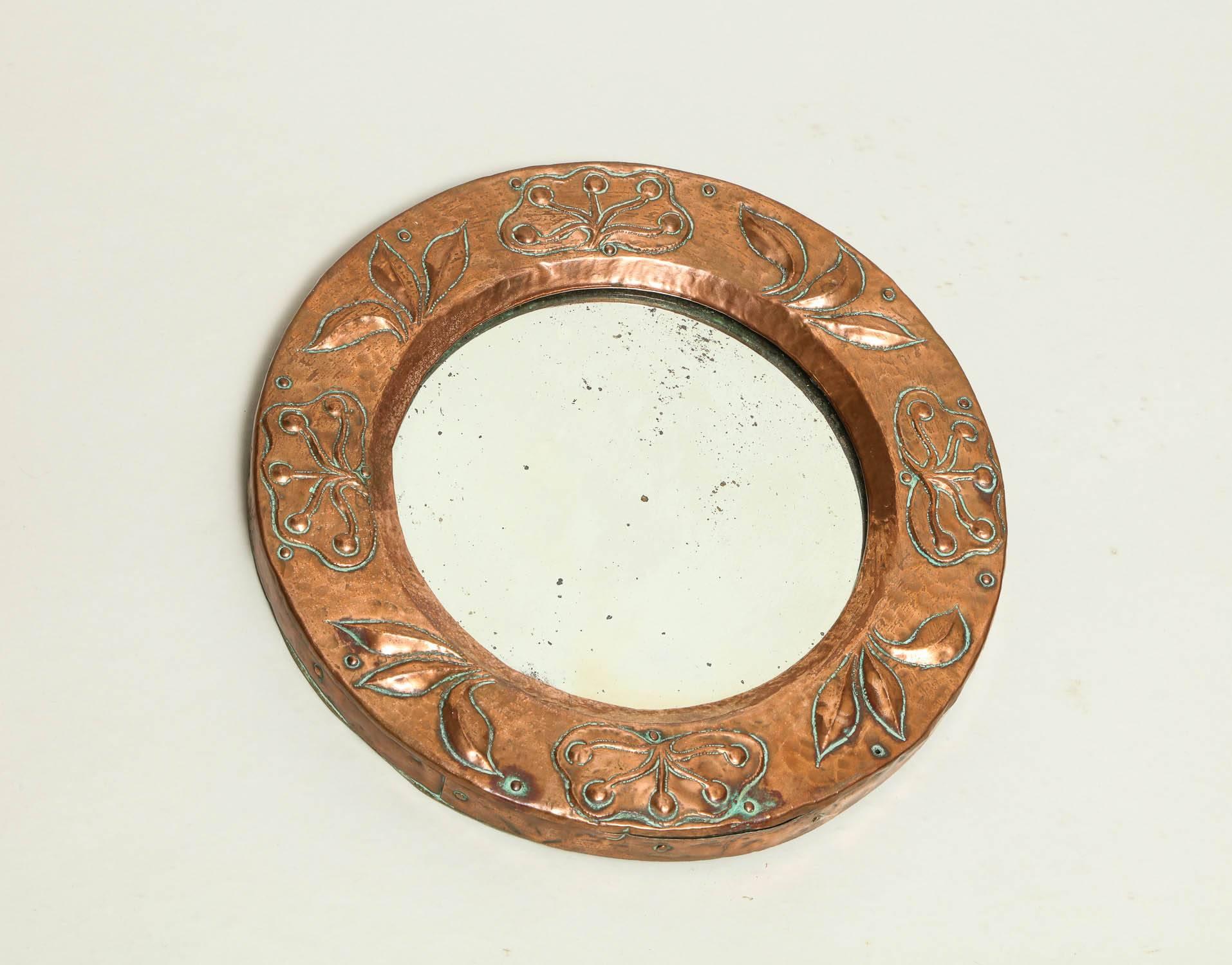 A diminutive English Arts & Crafts round mirror with copper frame having repousee leaf designs and a bevelled glass centre English, late 19th century.
  
