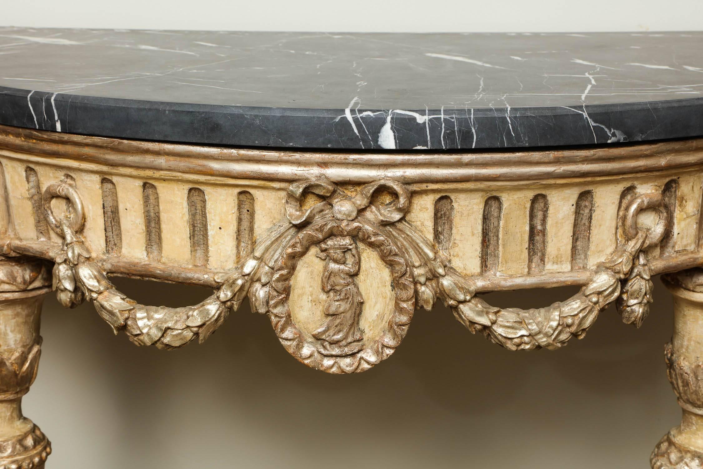 Fine pair of 18th century Italian neoclassical demilune console tables, the later shaped white veined black marble over fluted apron adorned with swags and central medallions, standing on turned, carved and fluted legs and standing on foliate carved