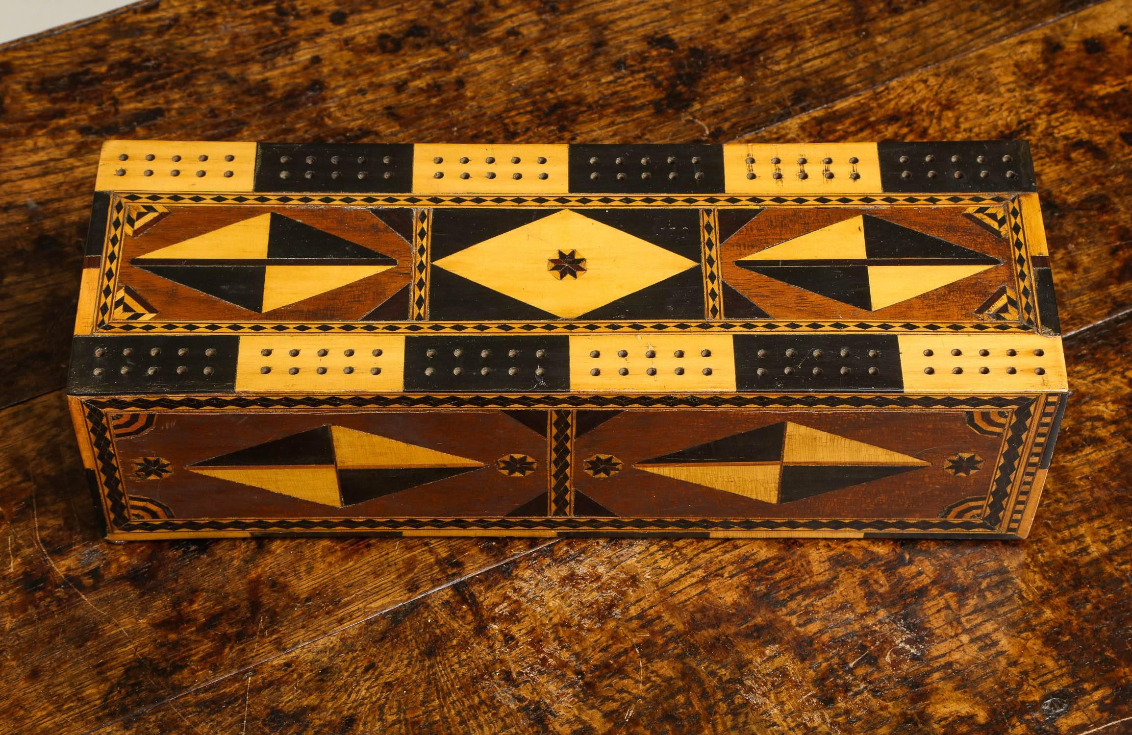 Very fine English mid-19th century cribbage box with striking geometric and contrasting colored inlay, composed of ebony and holly, the body of the box in mahogany, the storage drawer with turned bone handle, original lining paper and in overall