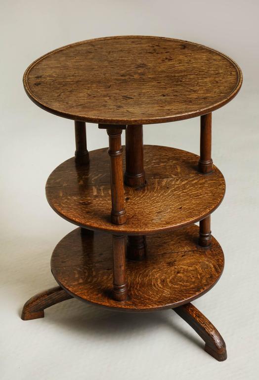 An early 19th century English end table having three round tiers, the upper with a dished top, supported on three ring-turned columns and standing on arched feet, all in vividly grained oak.