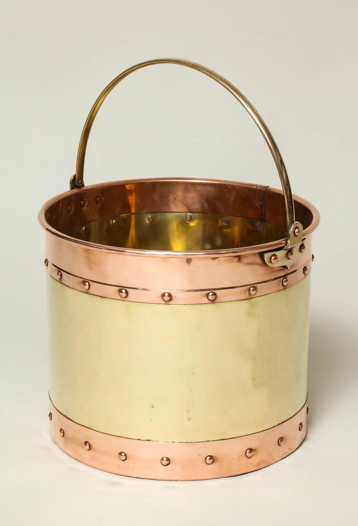 Good early 20th century brass and copper kindling or wastepaper bucket with brass bail handle over riveted bands of copper flanking brass body, recently well polished and of good sturdy weight and construction.