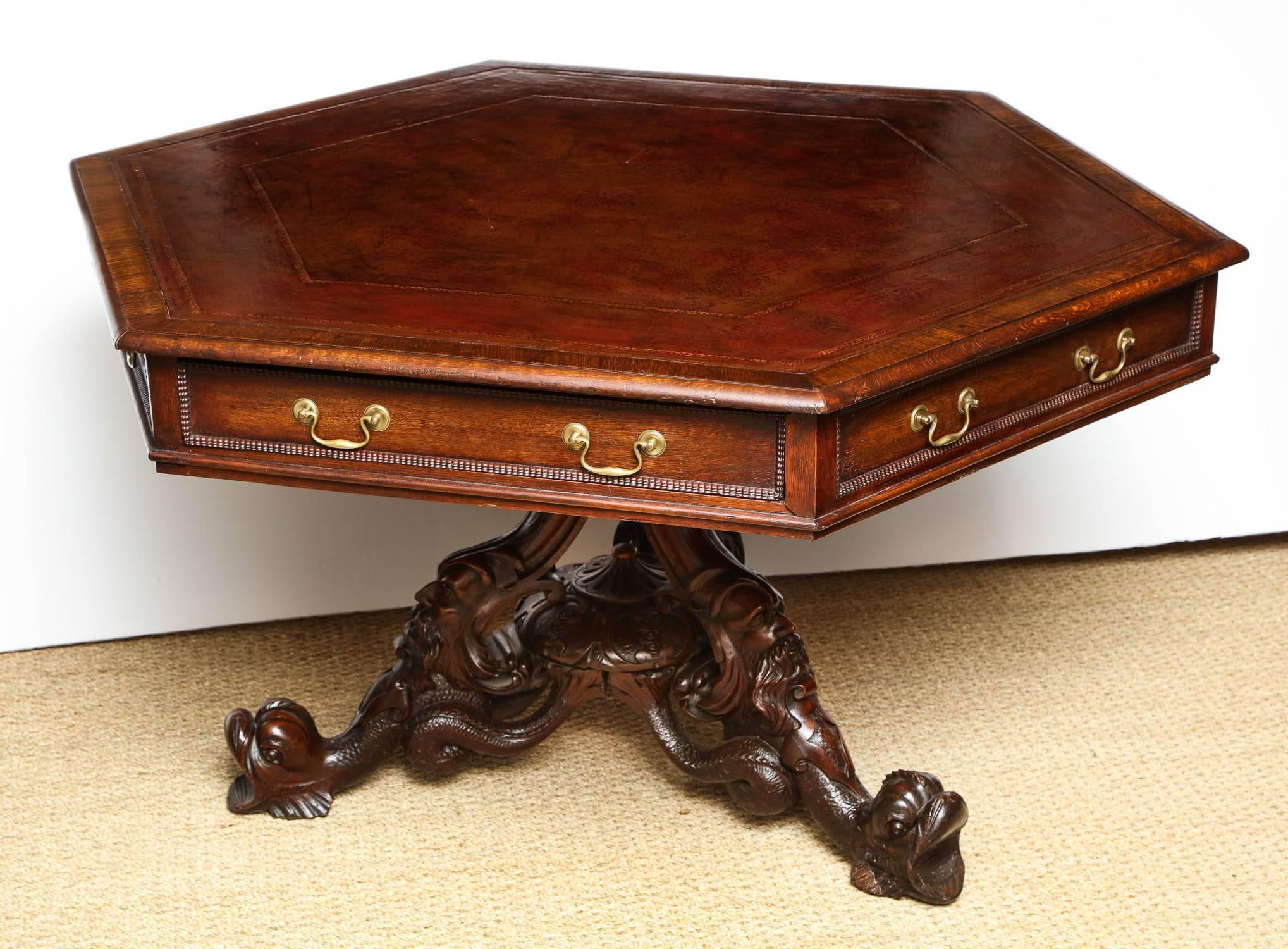 Mid-19th century English hexagonal library table by T. H. Filmer & Sons, London circa 1840, the gilt tooled Morocco leather top over three working and three dummy drawers with ripple moldings, the base carved with the head of Aeolus on dolphin