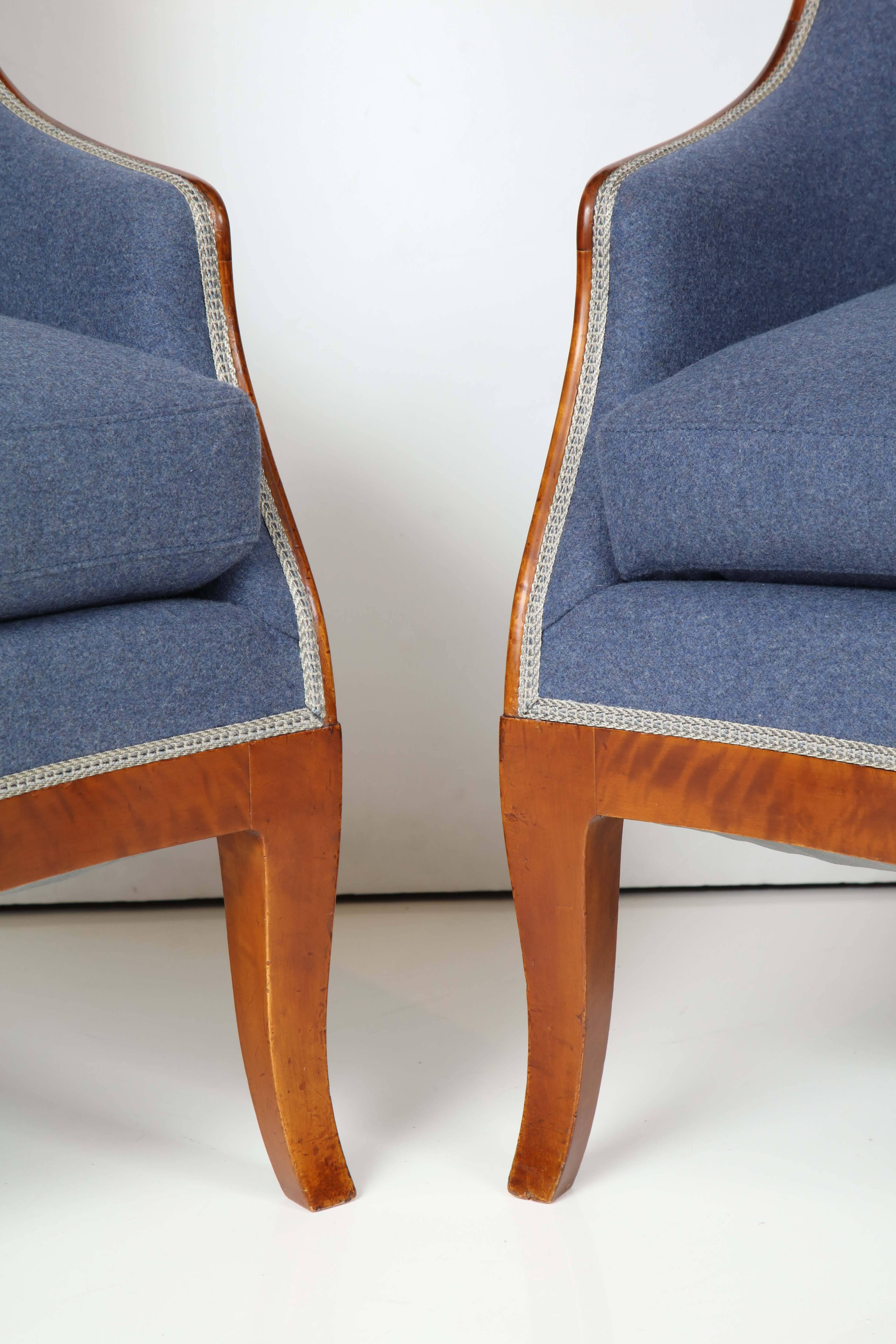 A pair of Swedish Grace birchwood highback armchairs, by Nordiska Kompaniet, Original design, circa 1918. This pair stamped Ca. 1919. Graceful curved backs and outcurve legs. Restored and reupholstered in grey and blue wool.