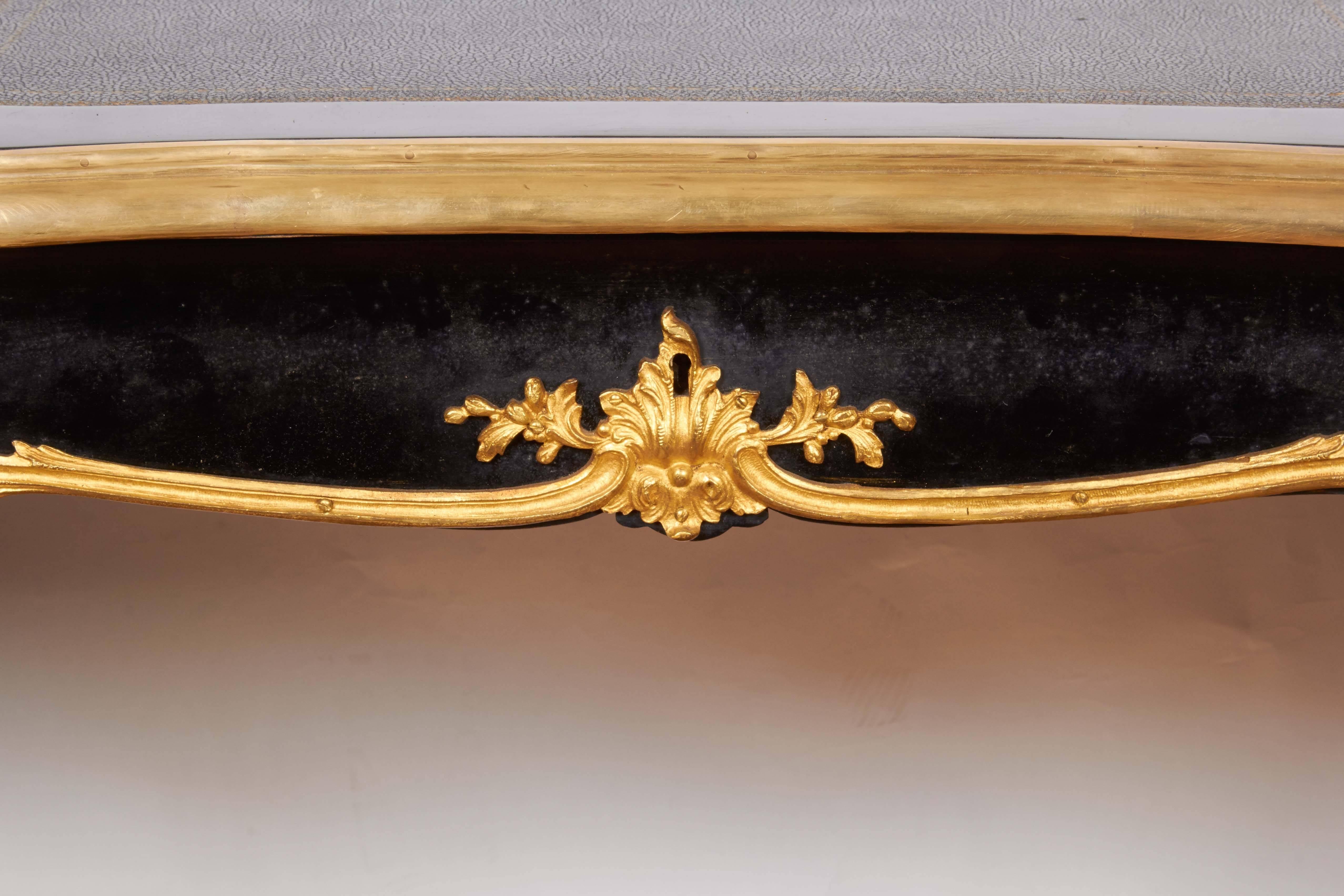 An ormolu-mounted ebonized bureau de dame in the manner of Francois Linke, serpentine top inset with gilt-tooled leather writing surface above a frieze framed with trailing foliage, acanthus and shell clasps, the angles with Grecian maiden terminals