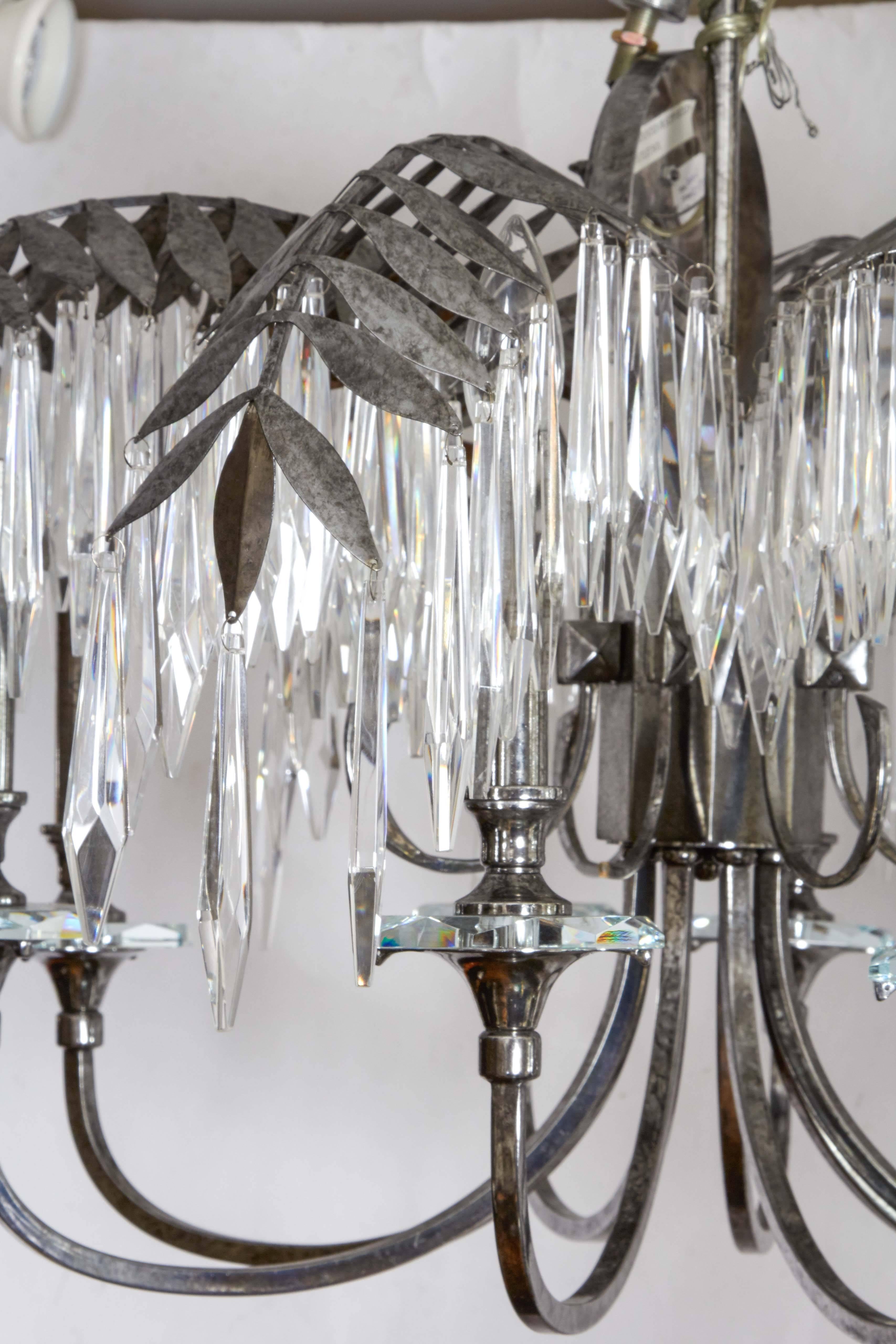 A silvered metal chandelier, palm fronds issuing crystal prisms, the eight scrolled candle arm with crystal bobeches, late 20th century.