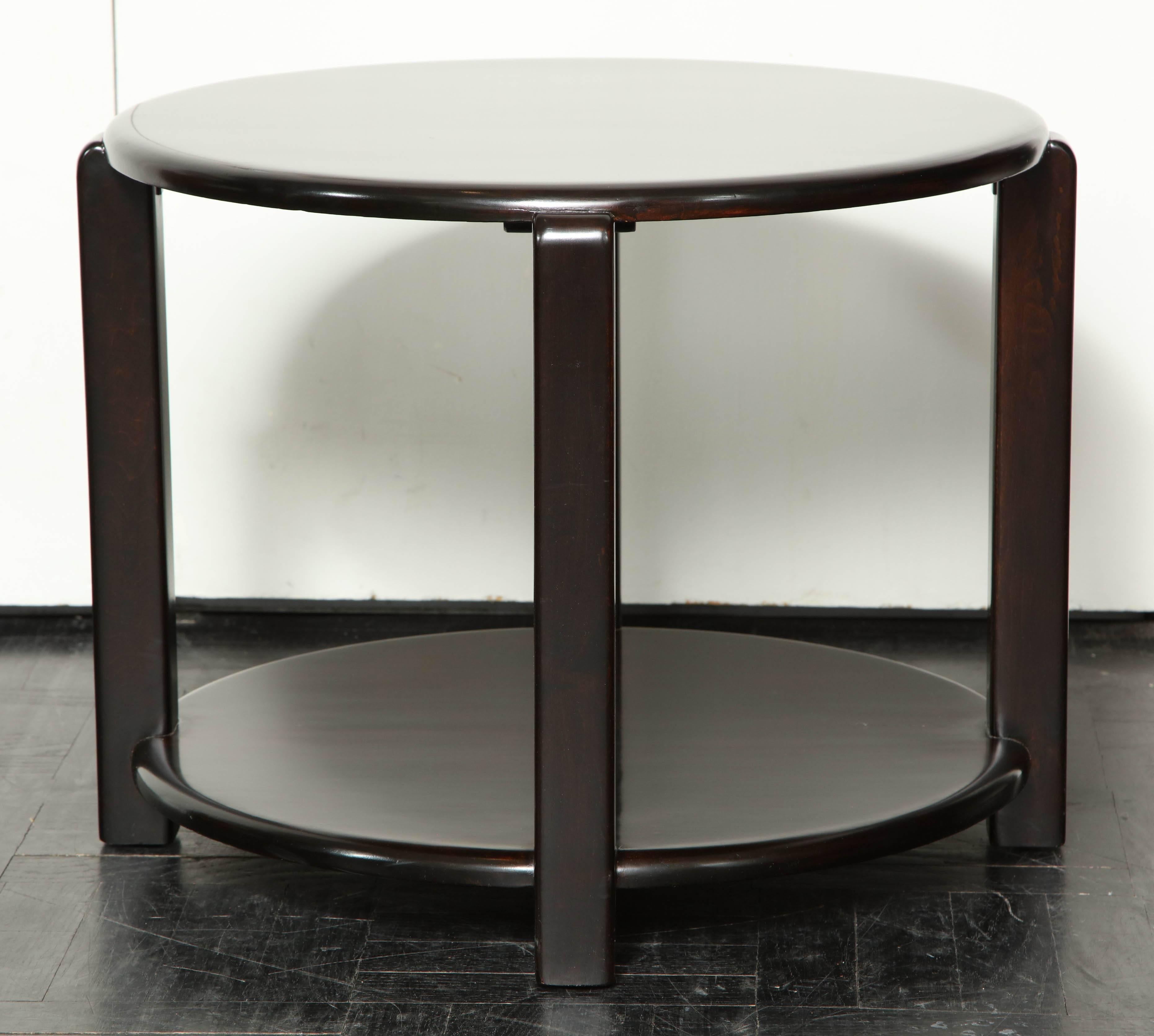 Mid-20th century two-tier ebonized walnut circular table, four polished supports.