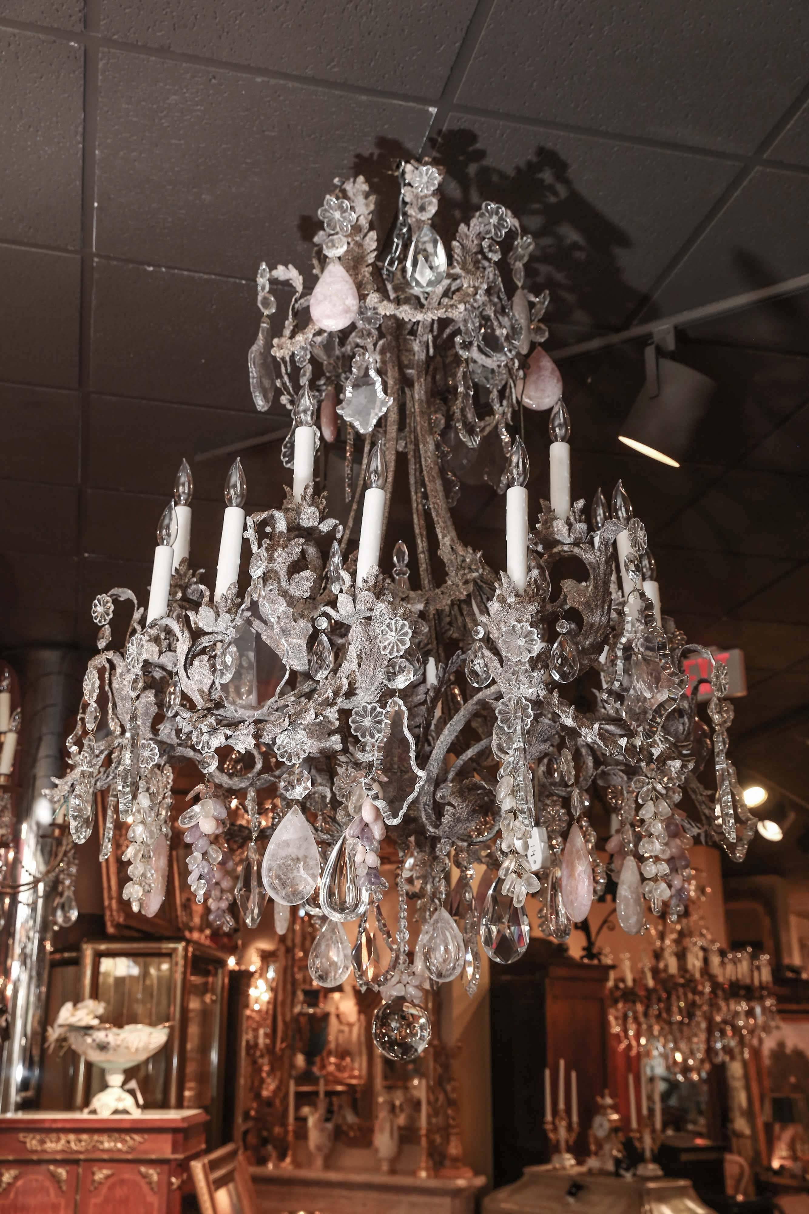This large piece has scrolling arms made of iron with an antique textured finish
it has clear crystal and rock crystal intermingled with rose quartz and amythest
Pieces. It has sixteen lights and it is in great working order.
