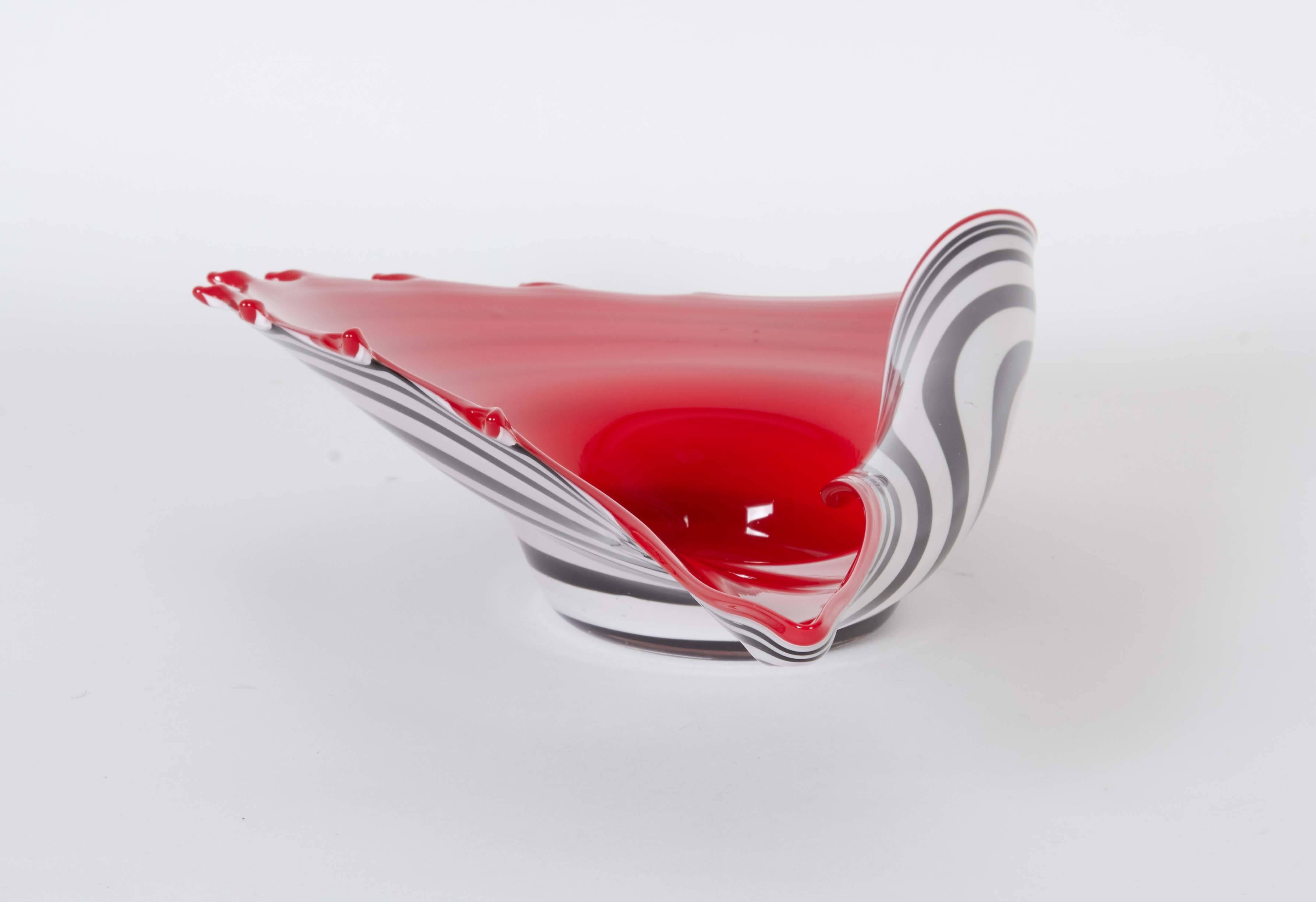 A modern style decorative bowl, crafted of Murano glass and designed as an abstracted conch shell, with bright red interior and black and white striped exterior, raised on single foot. Very good condition, consistent with age and use.

10955