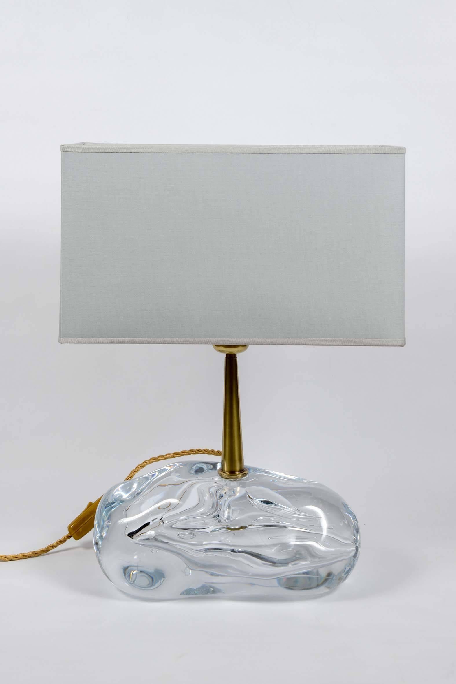 Pair of beautiful lamps made of a bloc of handmade clear glass with a brass stem holding the source of light and shade.

Esperia sticker on the socket, designed by Angelo Brotto.