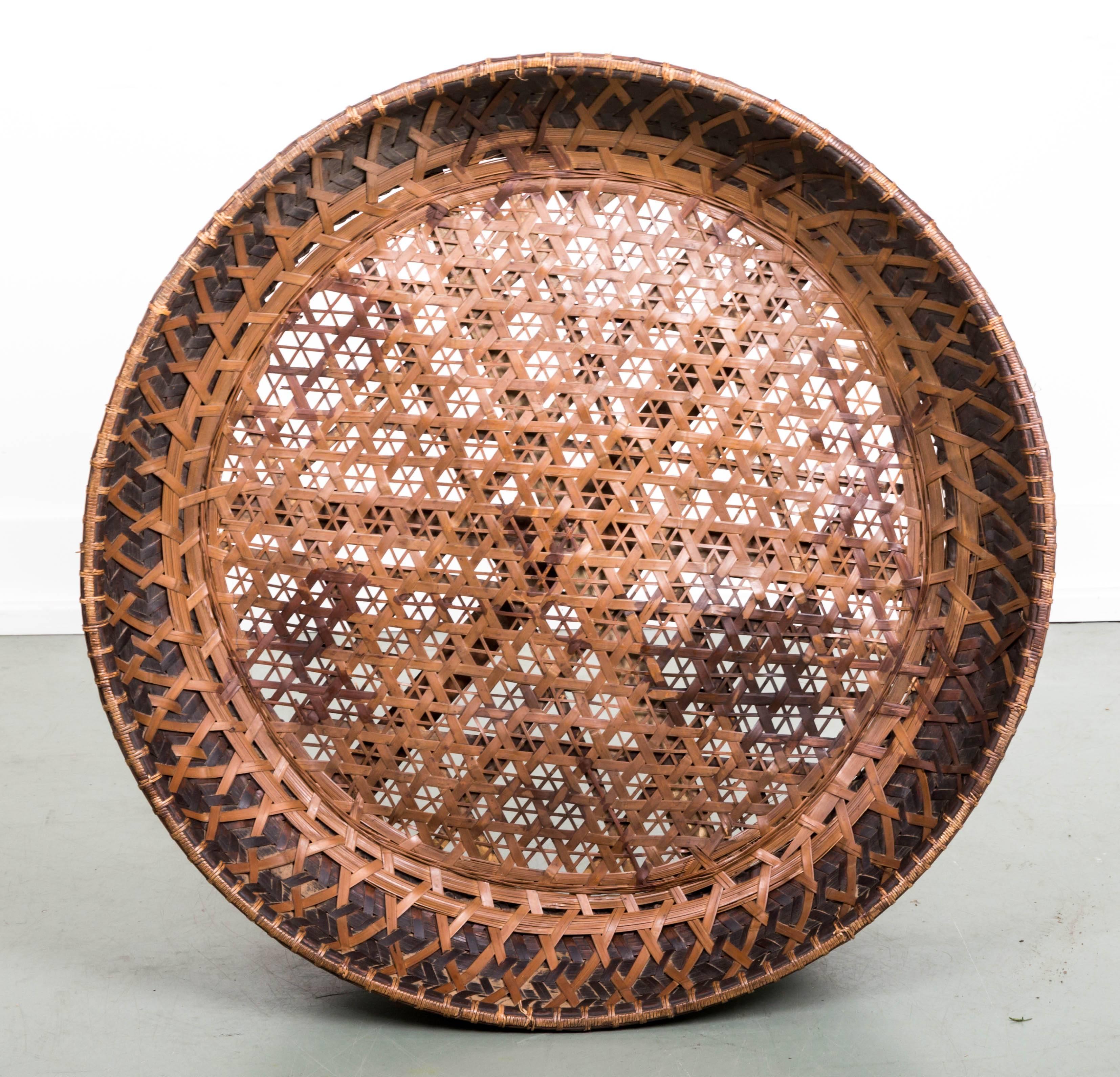 Late 19th century woven Asian tea basket. Intricate woven design, hourglass shape 31 inch;wide; 11 1/2 inch; high, old repair that has been rewoven. Wonderful patina decorative rivets holding woven rattan to bamboo frame.