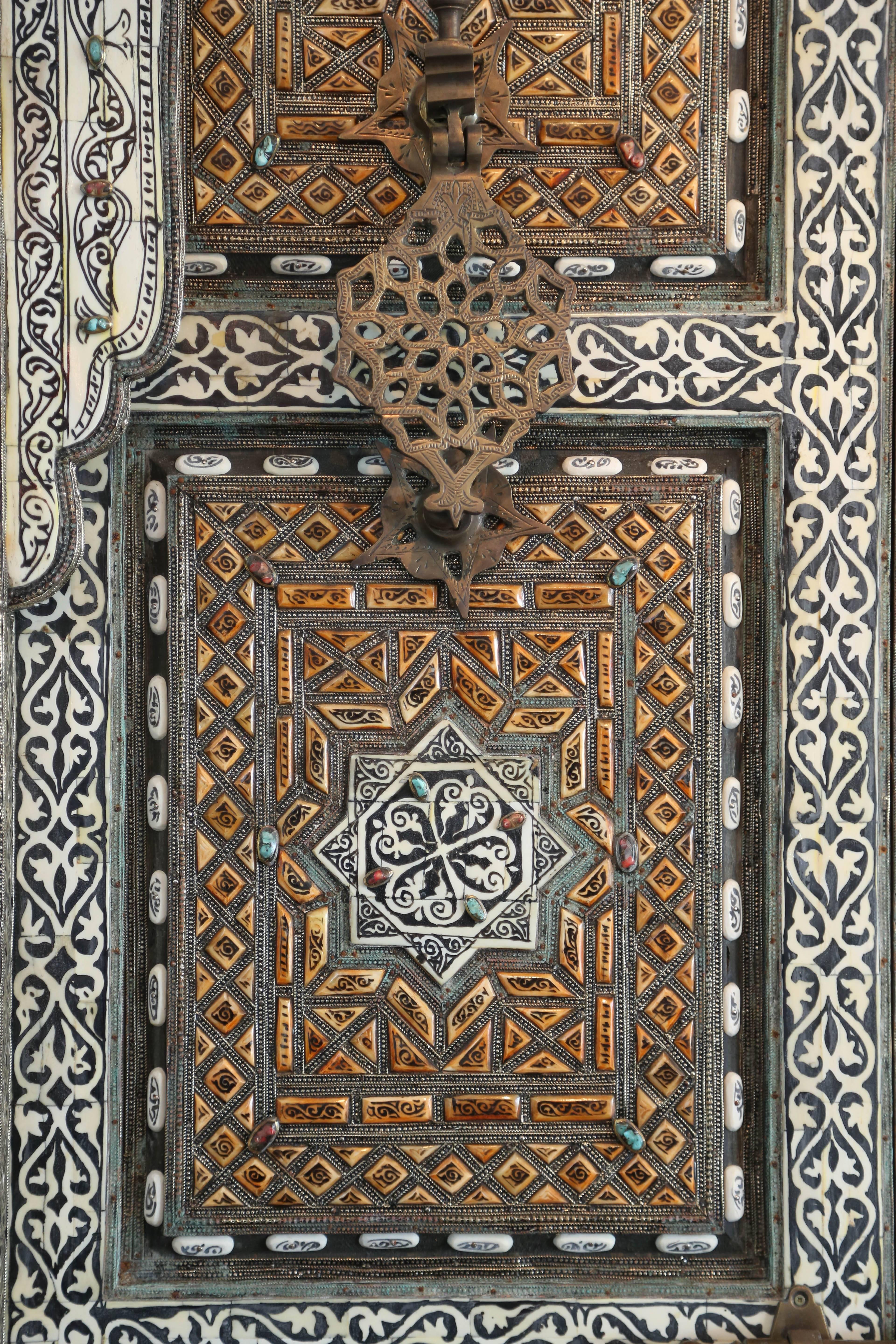 Exquisite Moroccan Palace door. Hand-carved camel bone and mousharabi work done by master craftsman. Brass crafted hardware. Adorned with semi precious stones, red coral and blue turquoise.
Door requires hinges to work.
Cutout size 99"1/4 H X