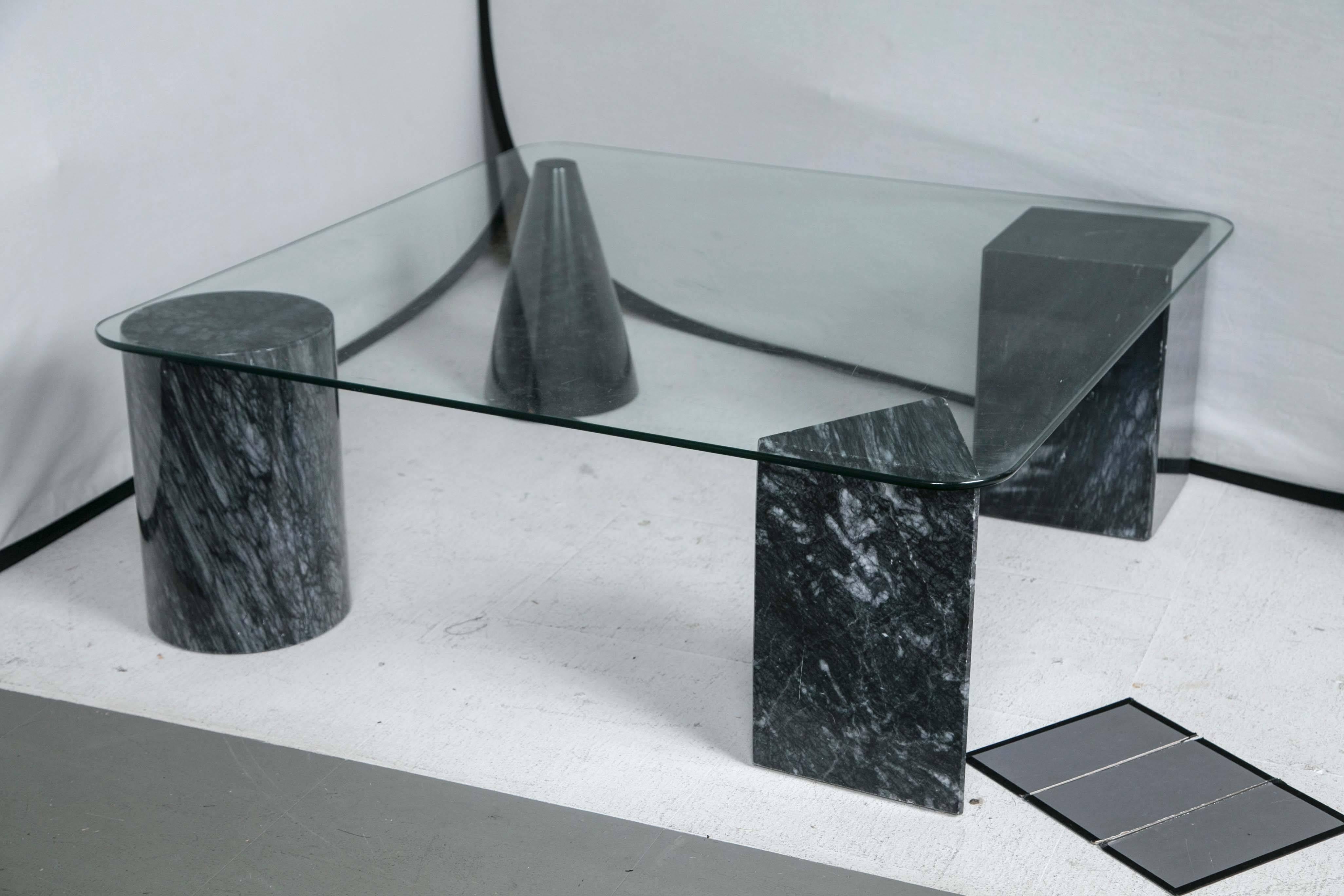 A glass coffee table with a geometric marble base.