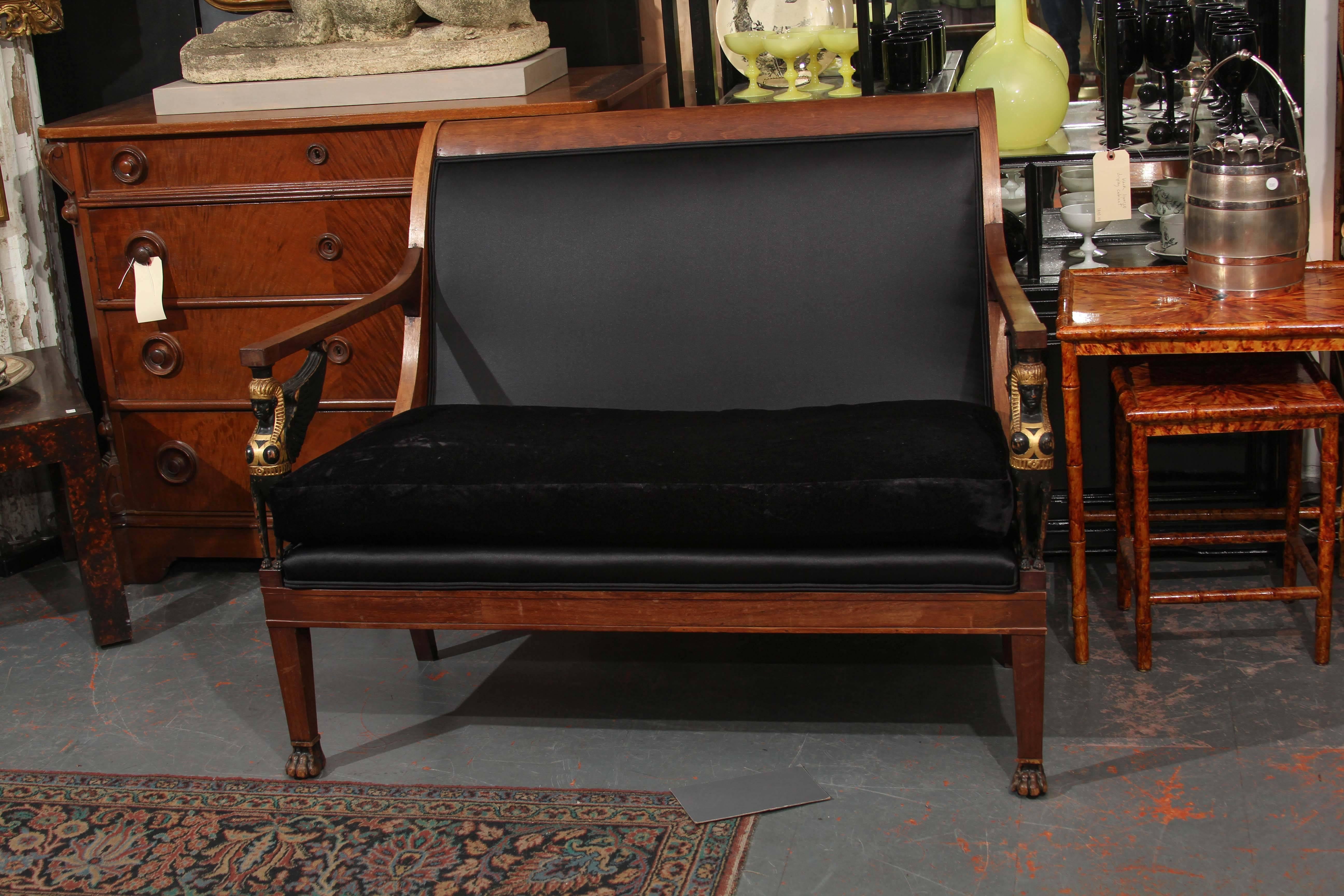 Egyptian Empire style small sofa/settee with carved wood winged sphinx armrests upholstered in black velvet and heavy sateen.
