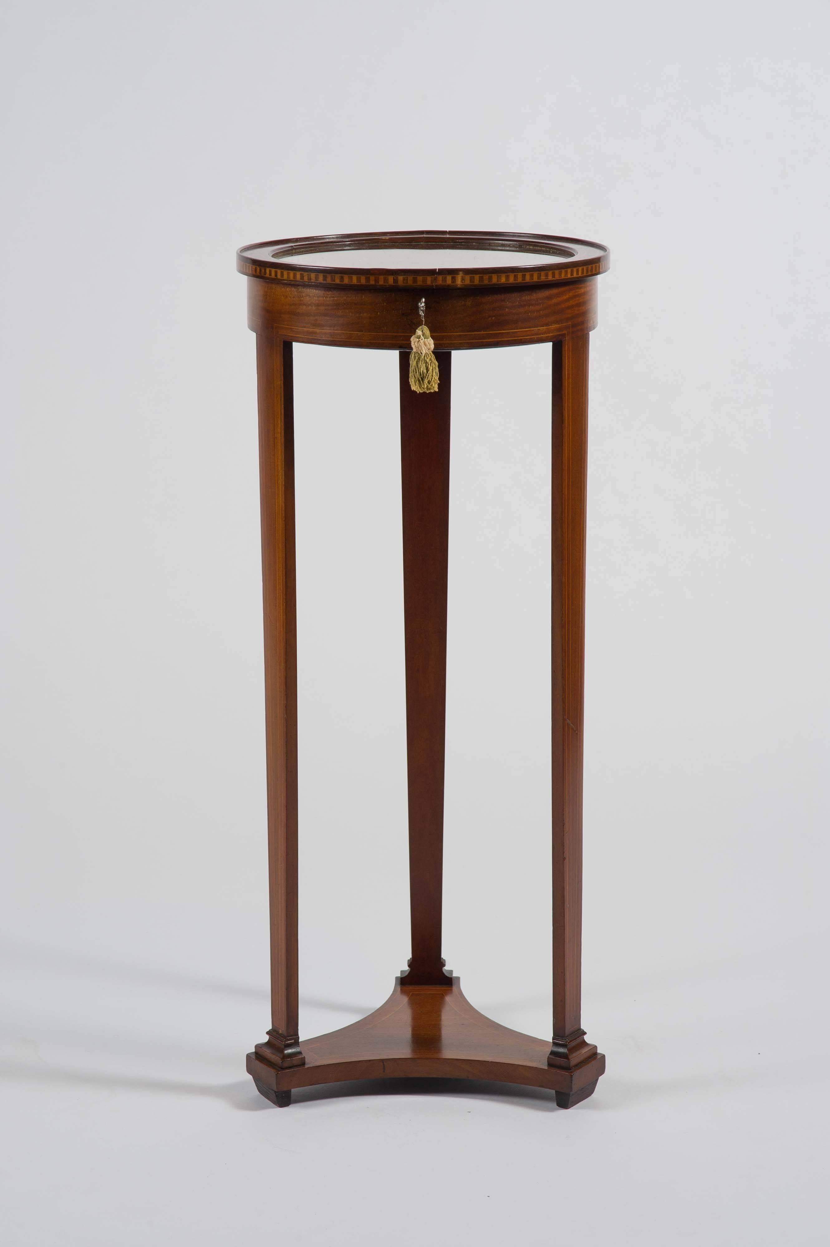 This delightful Edwardian table of mahogany with box wood stringing and inlay throughout of circular form, on three pillar legs and platform base. Lined with gold velvet, with working lock and key. Ideal for a watch, jewelry or cufflink collection.