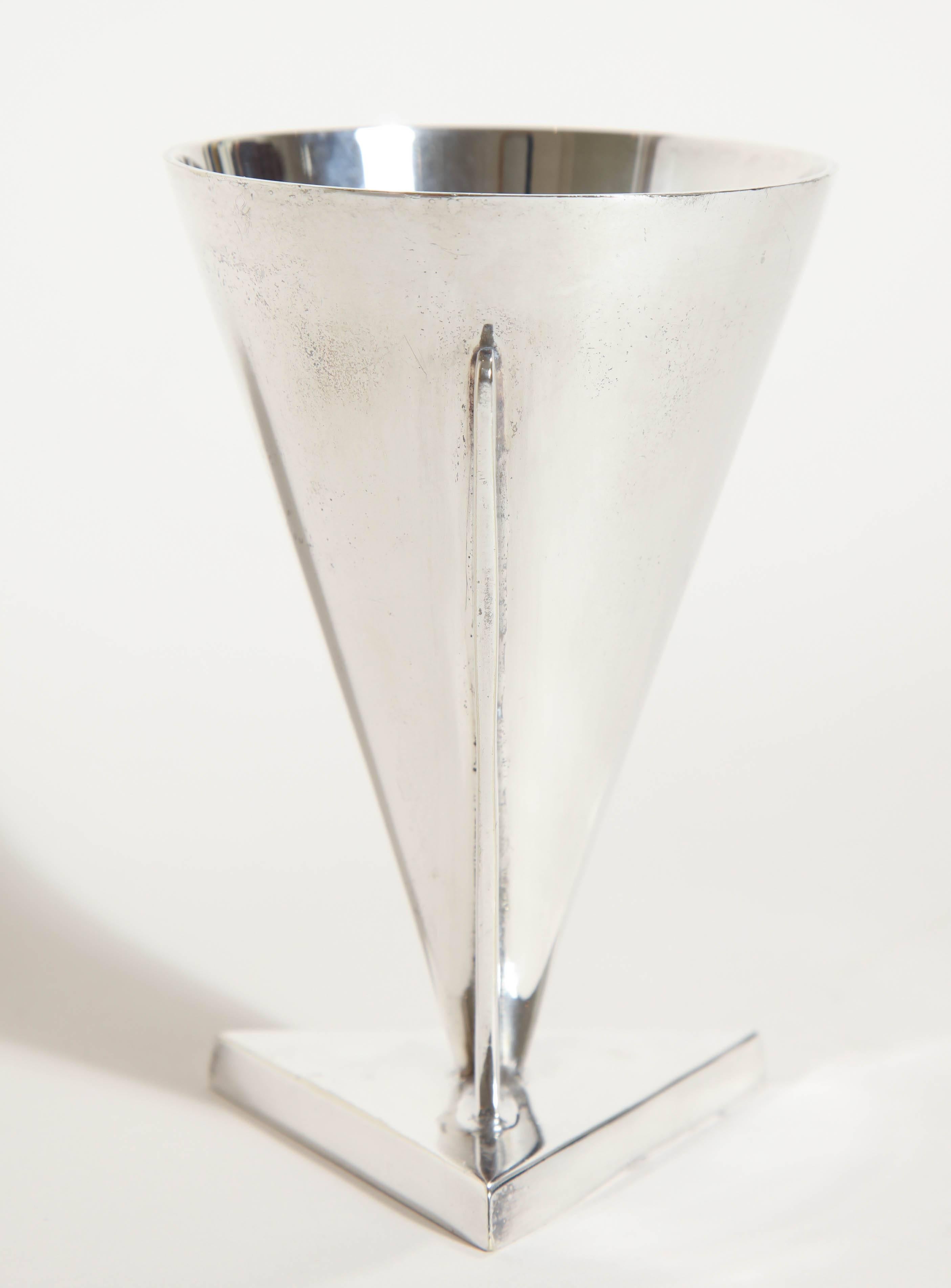 Conical cocktail coupe on triangular base supported by a tapering bracket.