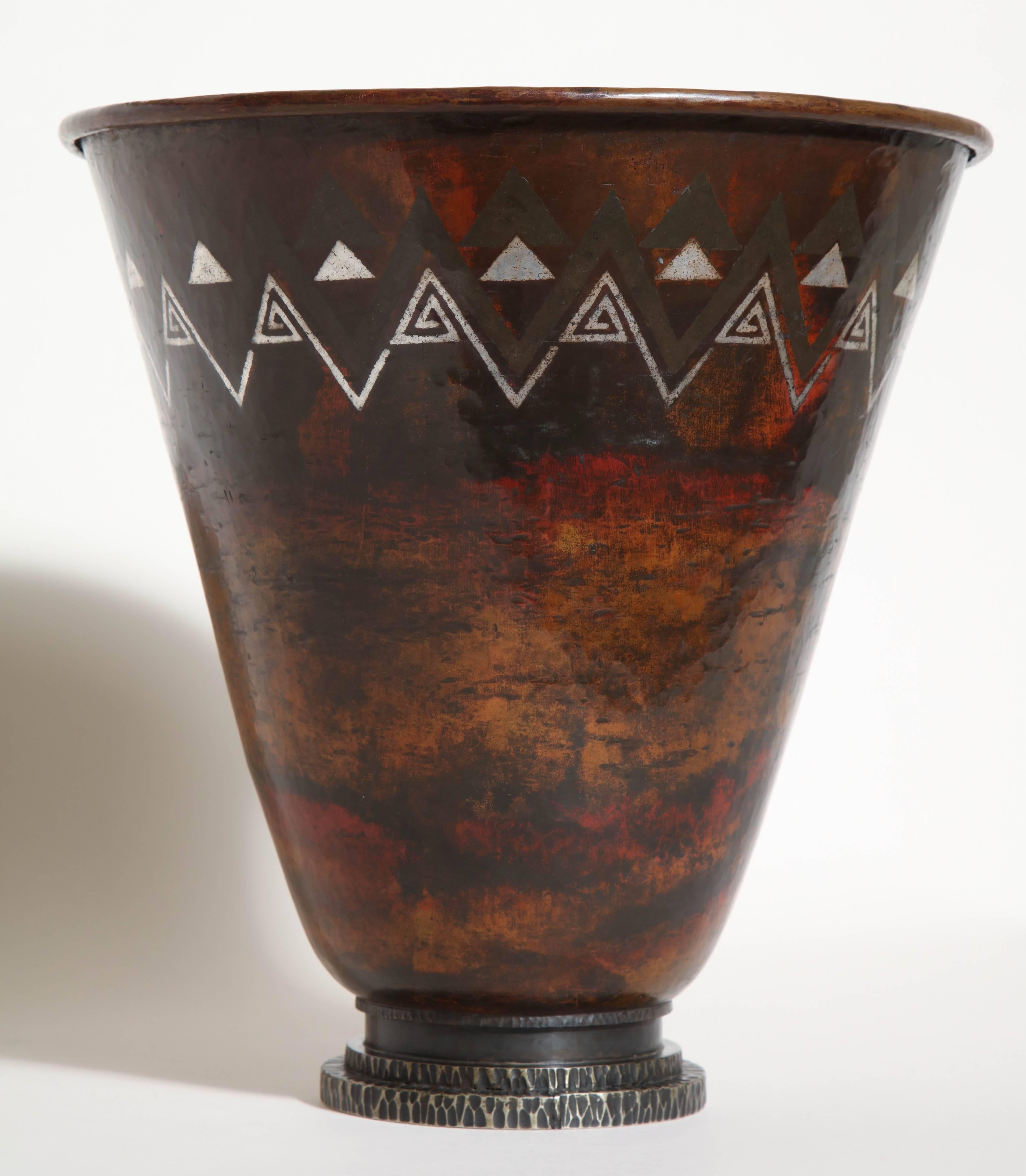 This exceptional flared cornet vase is decorated with fired patina and inlays of silver on background patinated with fire and red very richly nuanced with ocher and black. It rests on a wrought iron stepped base. 

Inscribed CL-LINOSSIER on the