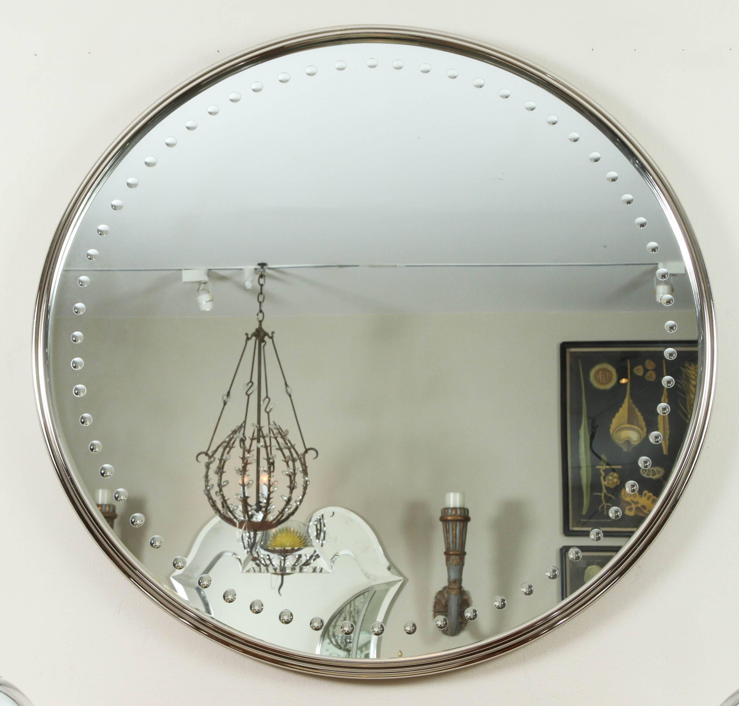 Large round mirror with reverse carved spheres and metal frame that has an antique silver finish.
