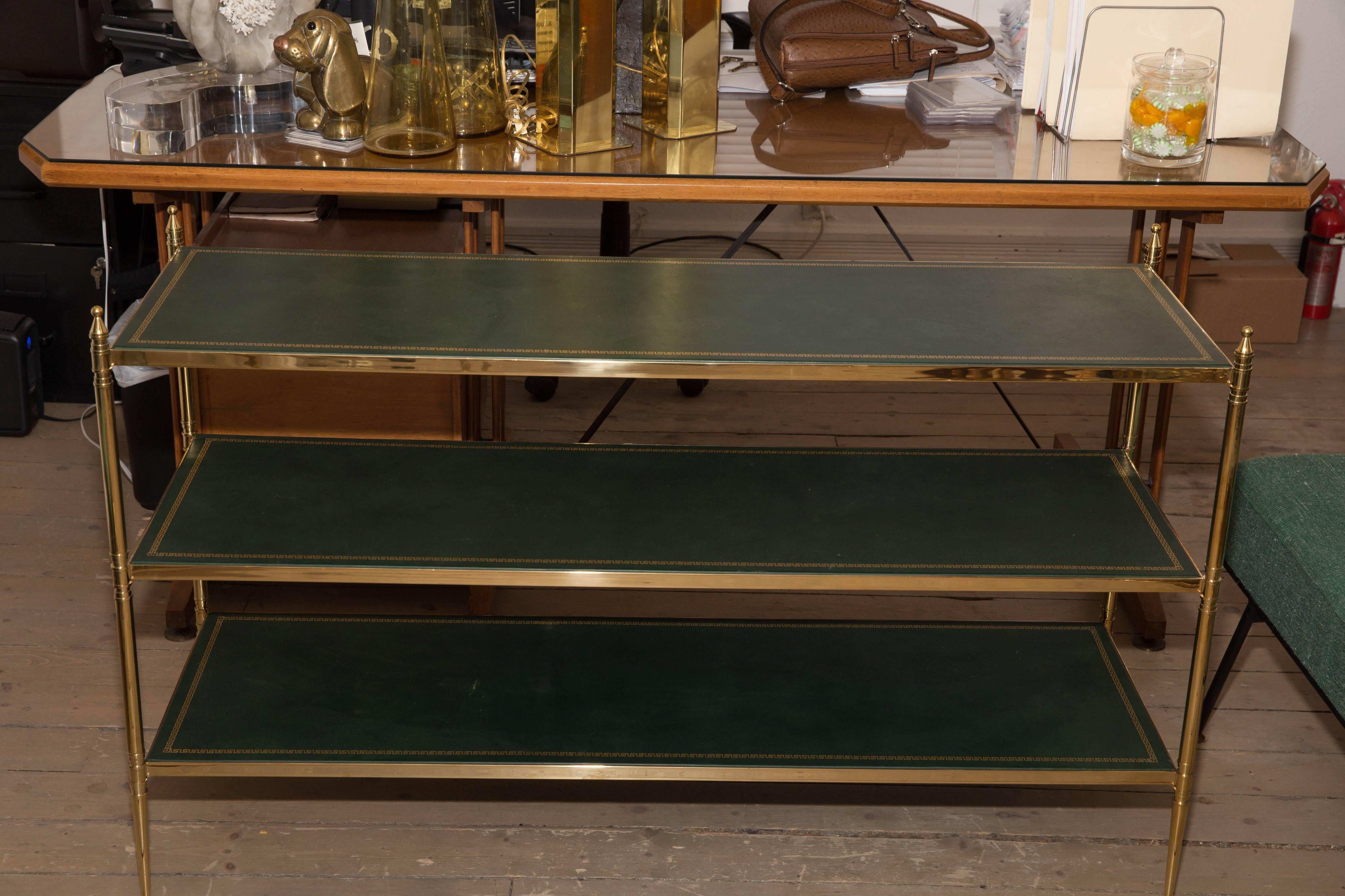 Three-tier brass etagere with green tooled leather top.