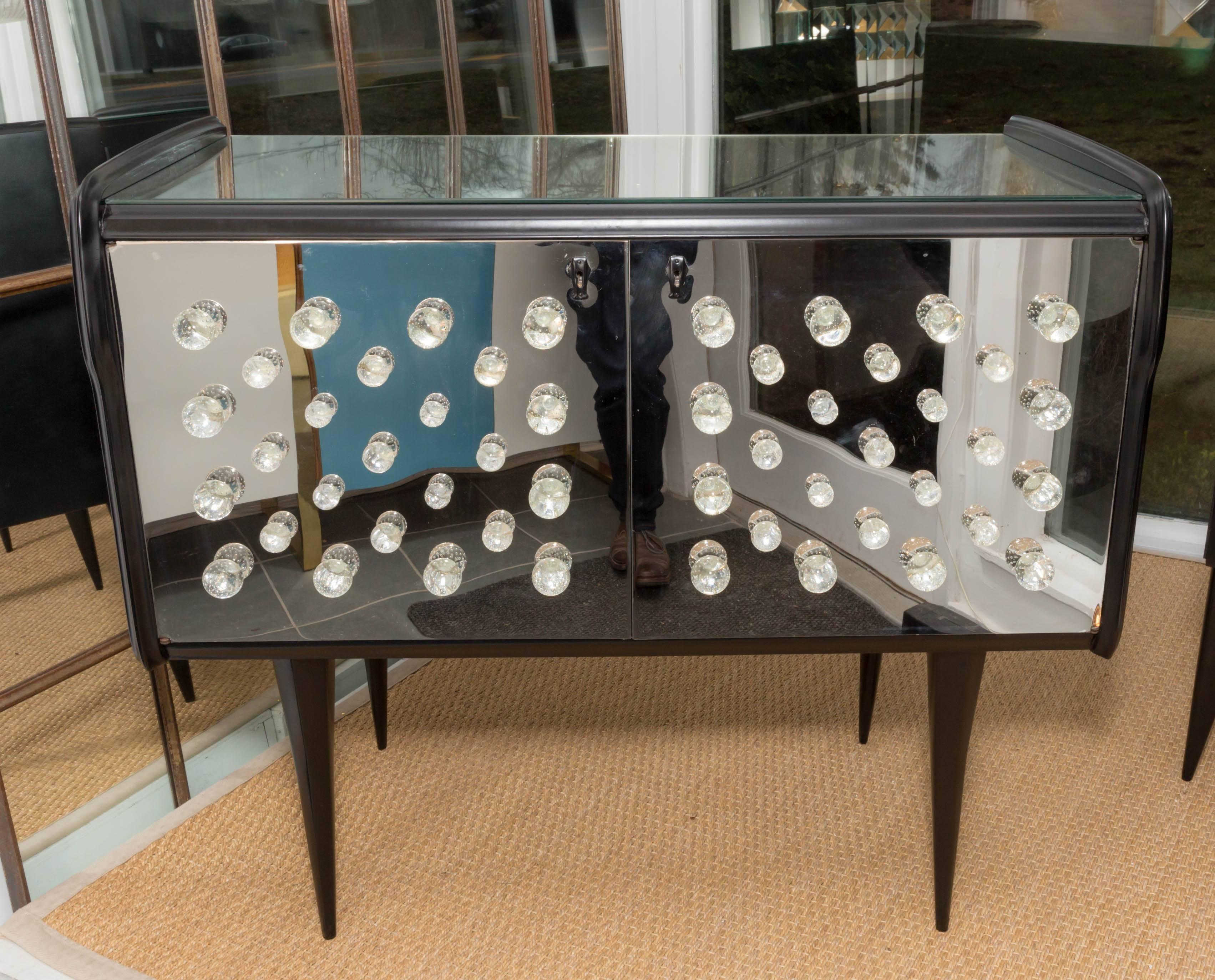 Pair of ebonized wood chests featuring doors with glass ball motif and mirrored tops.