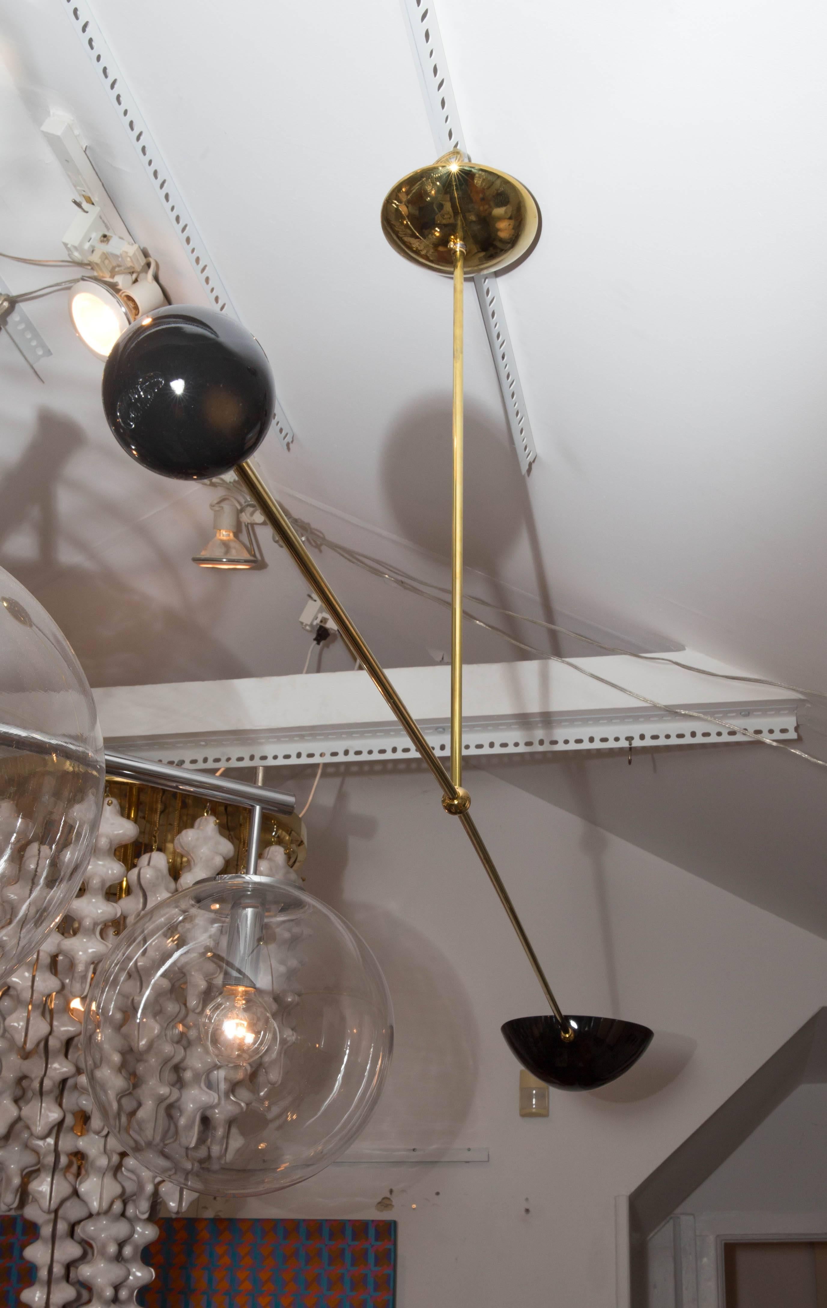 Single arm brass and black enameled metal ceiling fixture with articulated shade.